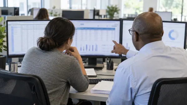 Two healthcare finance analysts review anonymized claims data on office monitors