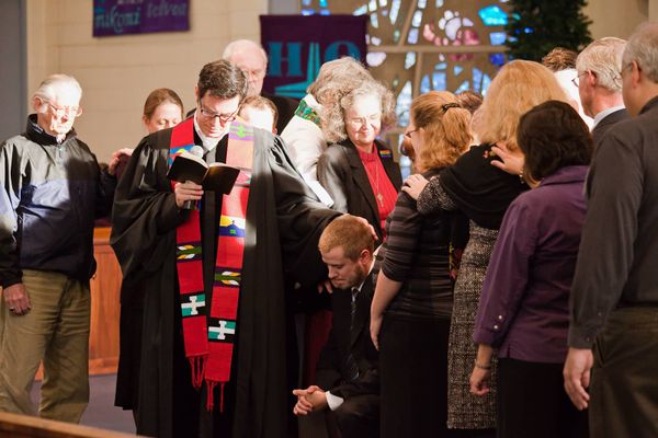 Group of pastors laying hands on a newly-ordained pastor