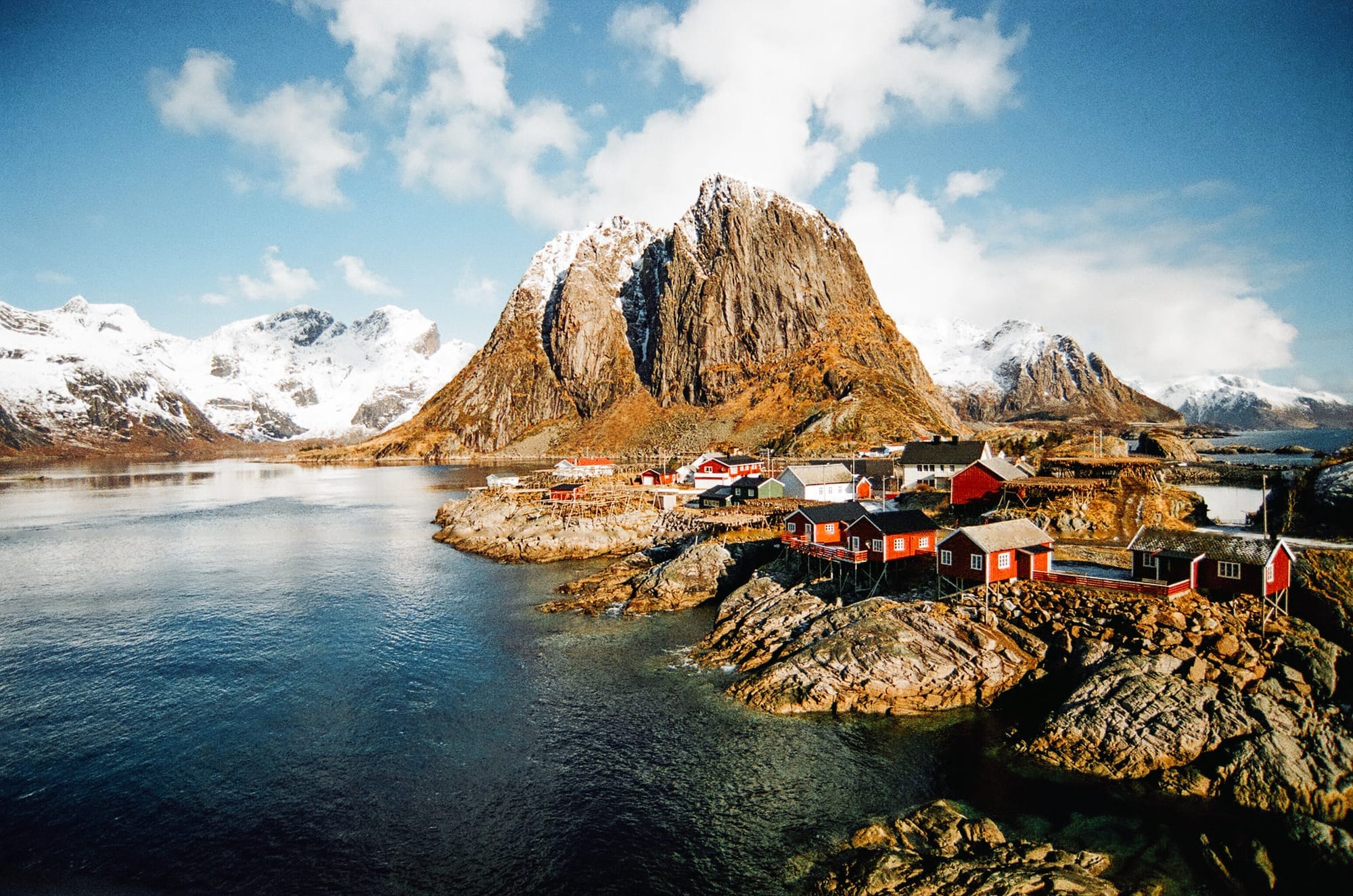 Lofoten landscape with colorful houses, a serene fjord and rugged peaks.