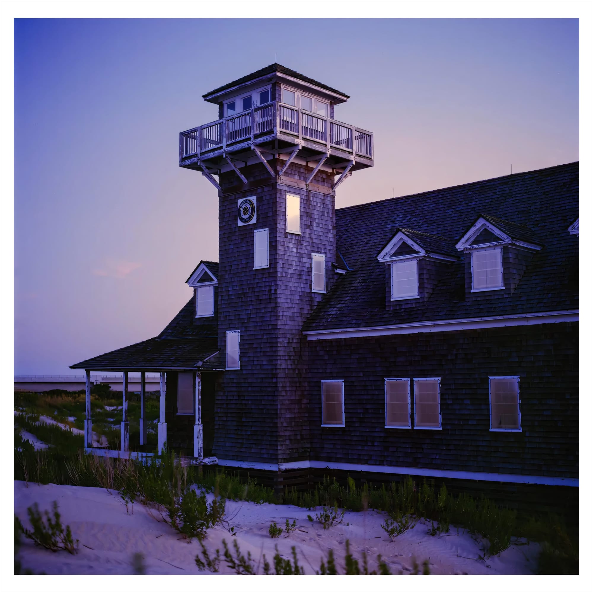 Old wooden tower house on a sandy dune during twilight.