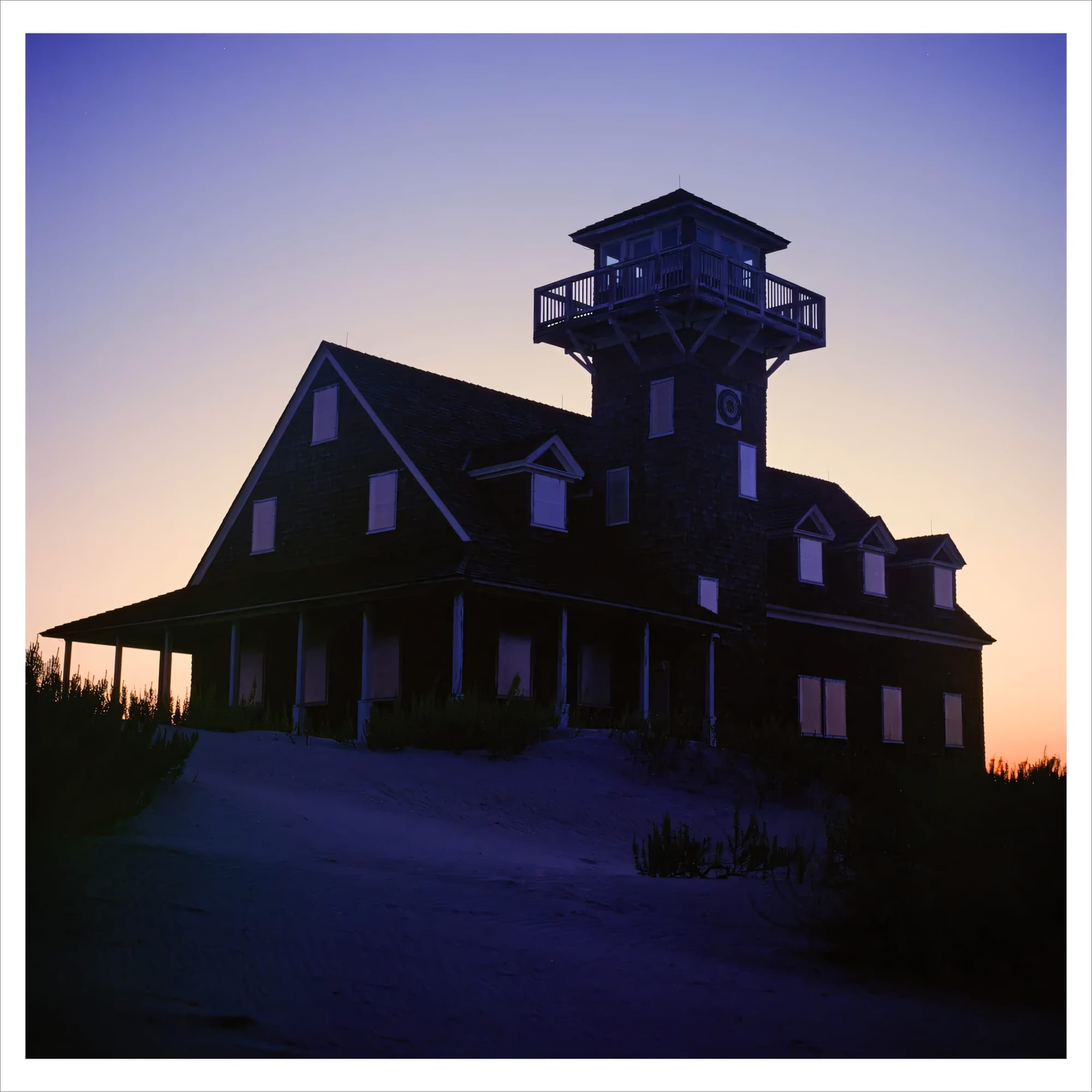 Silhouette of a wooden house with a tower at sunset.