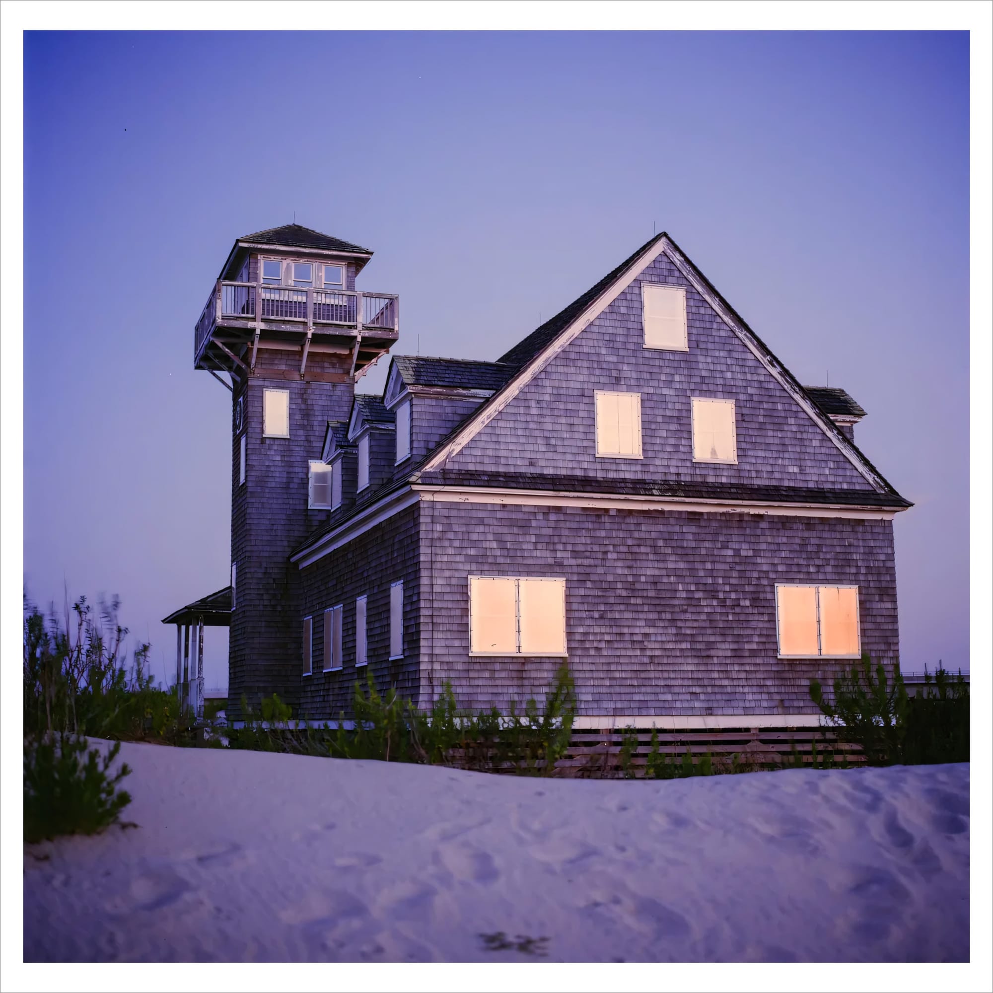 Old shingled house with a lookout tower at twilight.