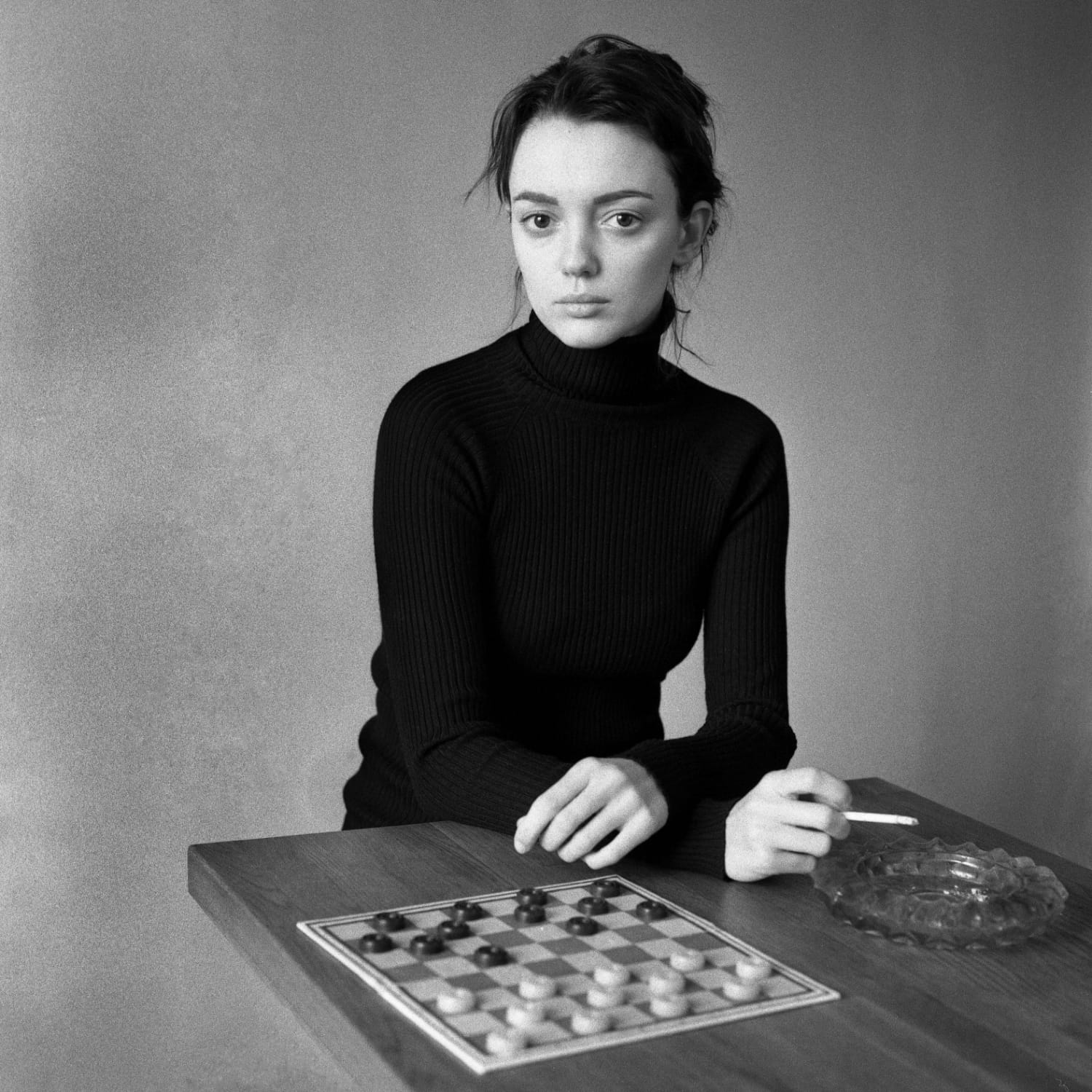 6x6 black and white portrait of a young woman, cigarette in hand, checkers on the table.