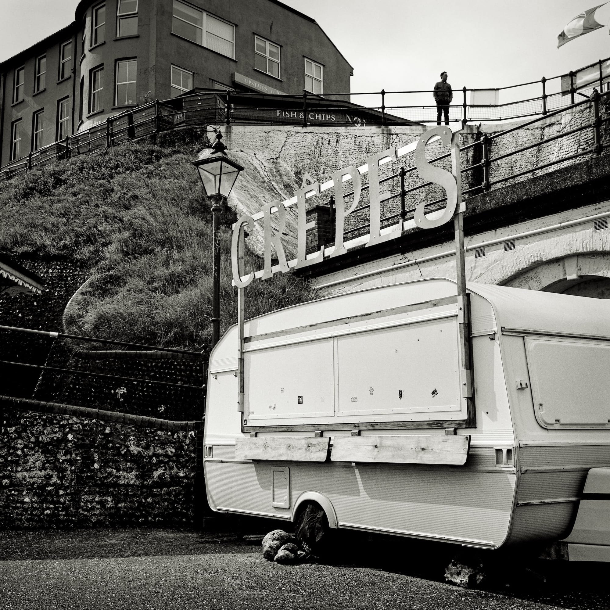 Black and white photo of a vintage caravan, with a sign reading "Crepes."