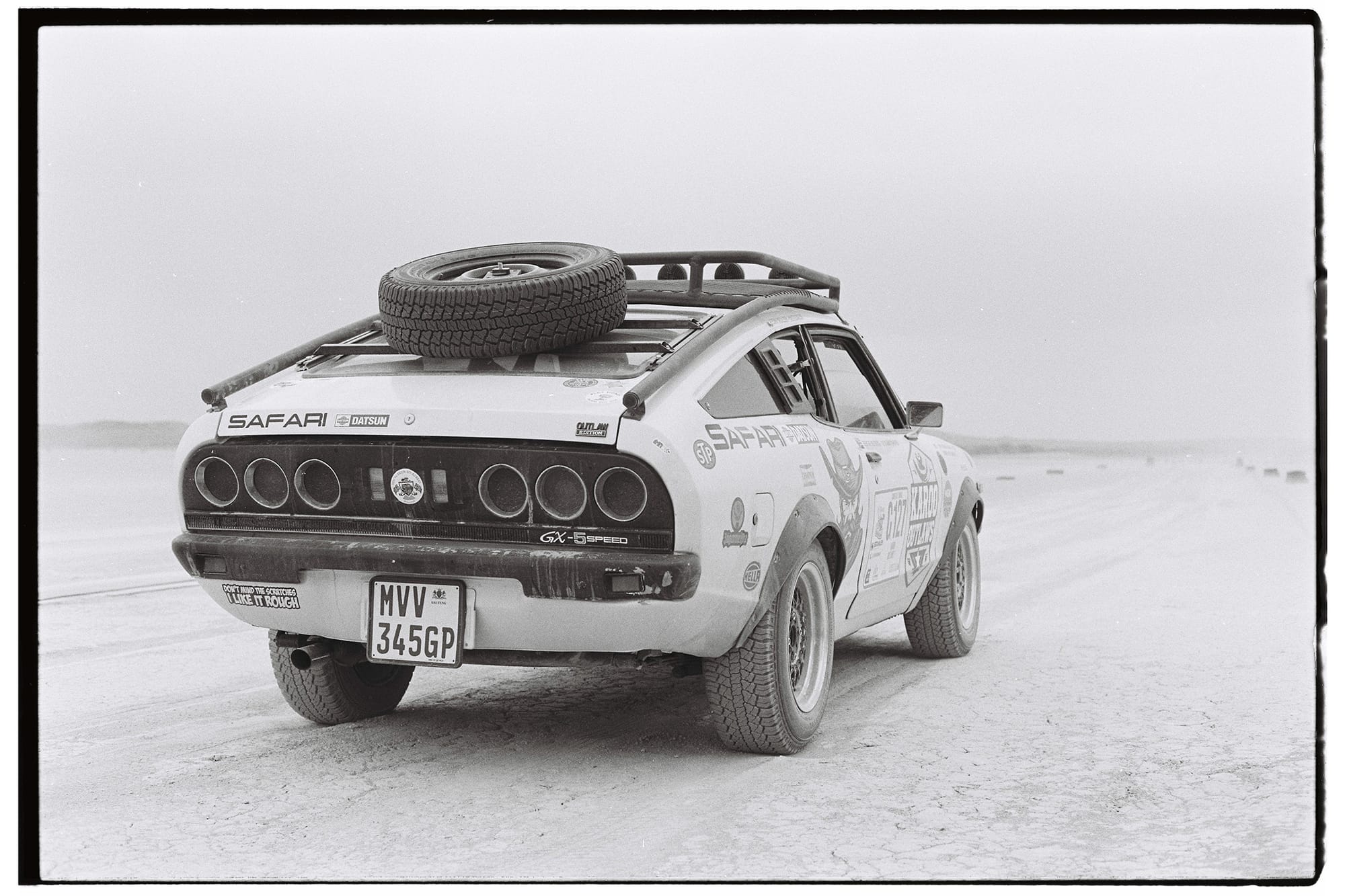 Datsun with roof rack and spare tire from behind on pan.