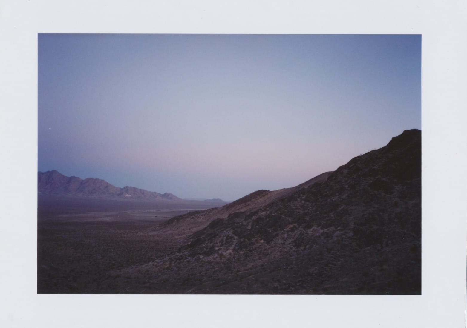 Desert hills at dusk with pink sky just before blue hour.