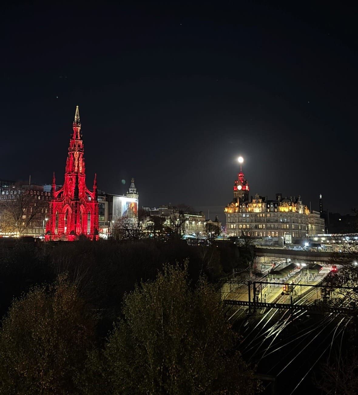 A city at night, with two buildings lit-up red. 