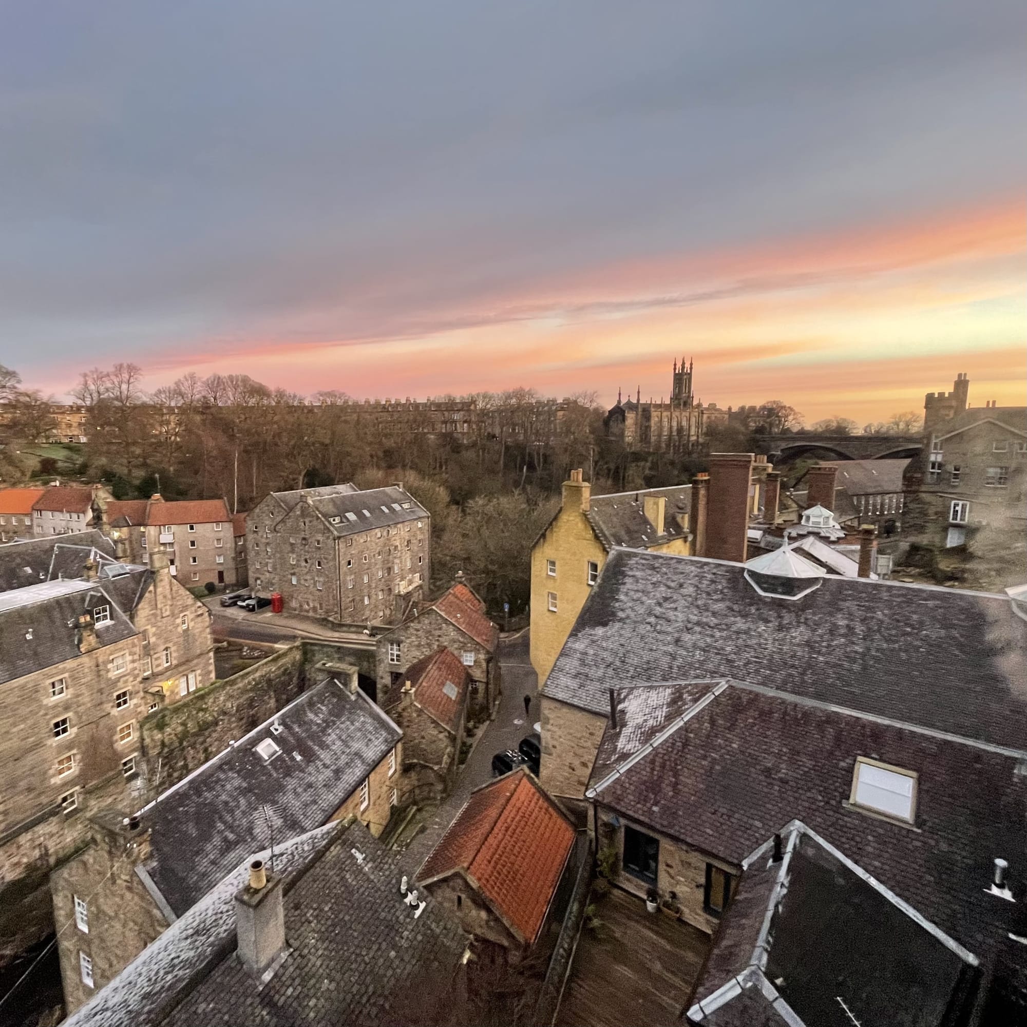 Clouds illuminated by sunrise over brick buildings and chimneys in Edinburgh’s Dean Village.