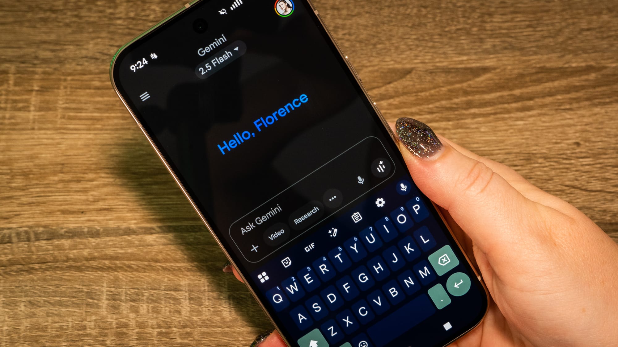 A photo of a person holding a Pixel 10 device with Gemini saying "Hello Florence" on the front