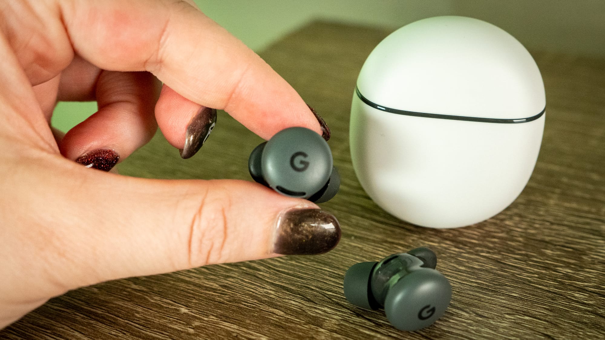 A person holding one of the Buds 2a in front of the charging case.