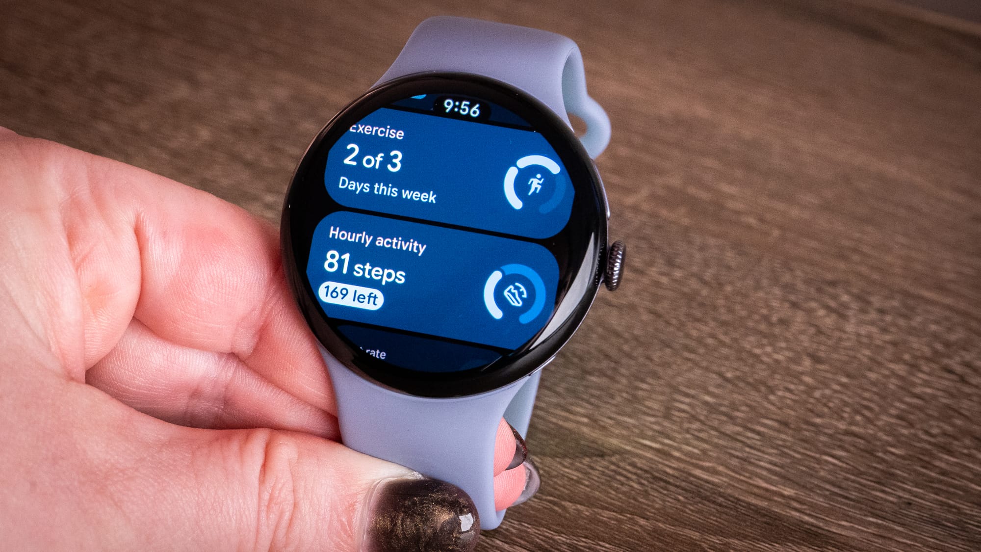 a photo of a person holding the pixel watch 4 and showing the Fitbit app