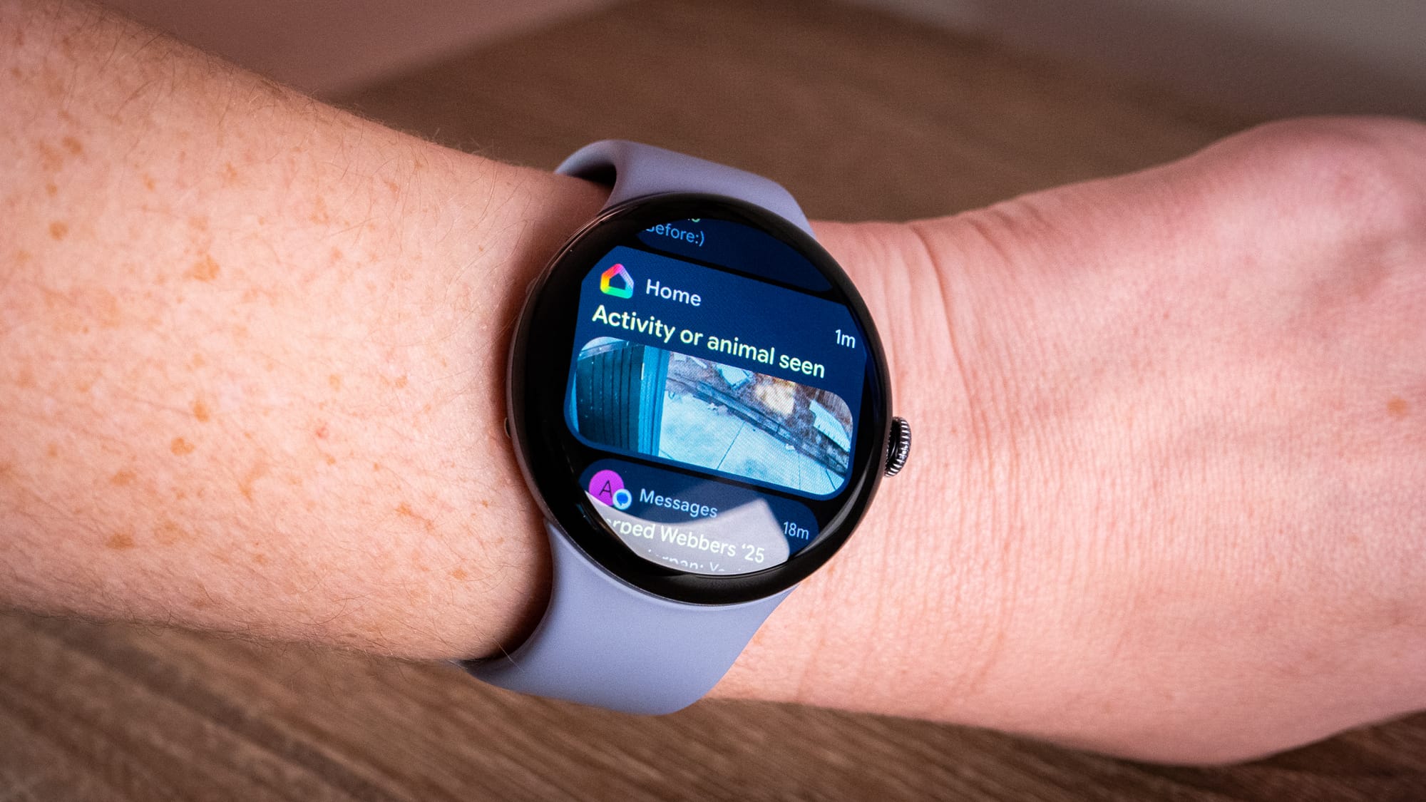 A photo of a person wearing the pixel watch 4 with the screen on a nest camera notification