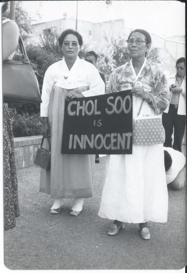 Two elderly Korean women wearing traditional dresses hold a sign that reads Chol Soo is innocent at a demonstration. Credit: Courtesy of Gail Whang. 