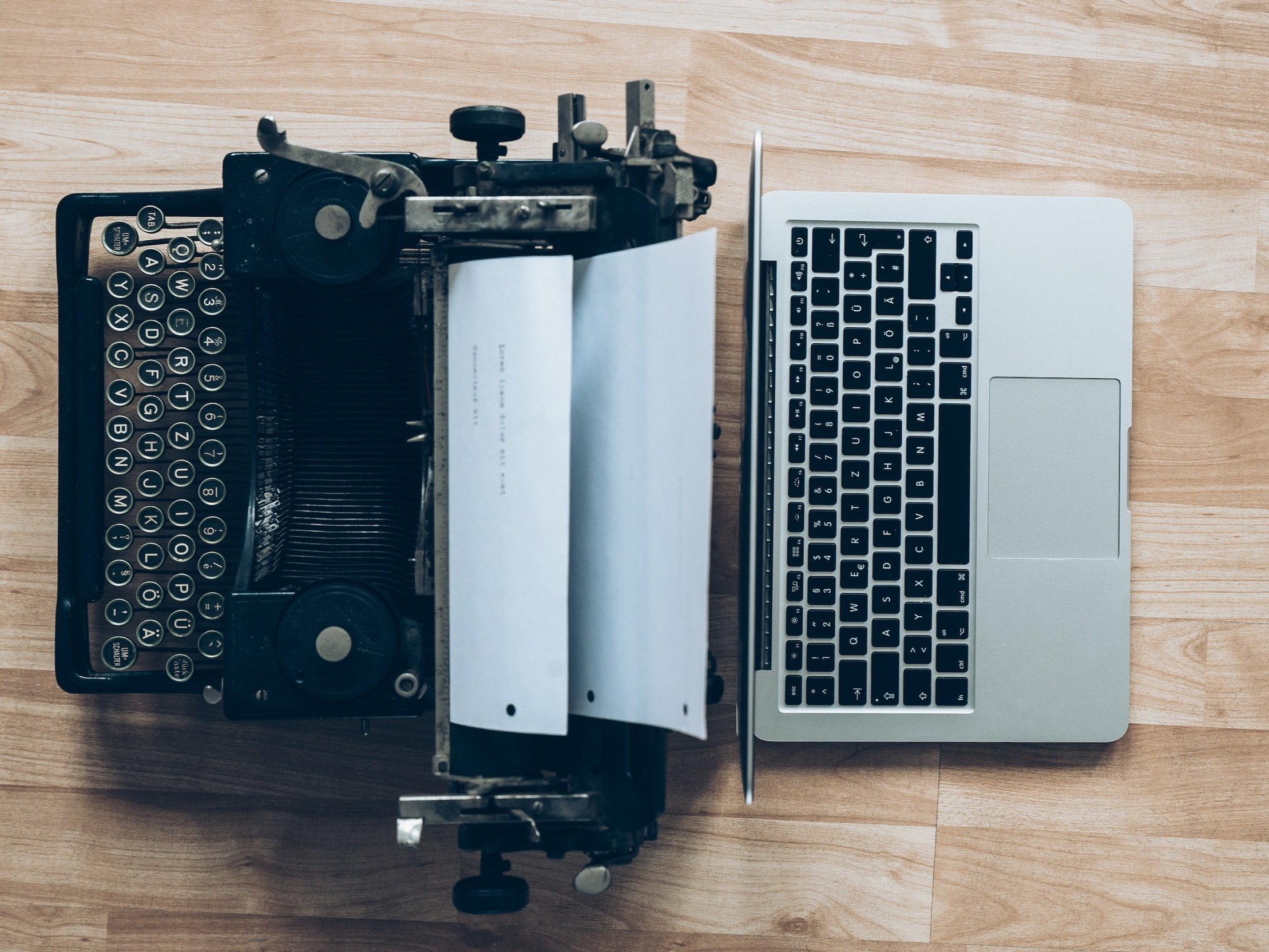 A vintage typewriter sits next to a Macbook.