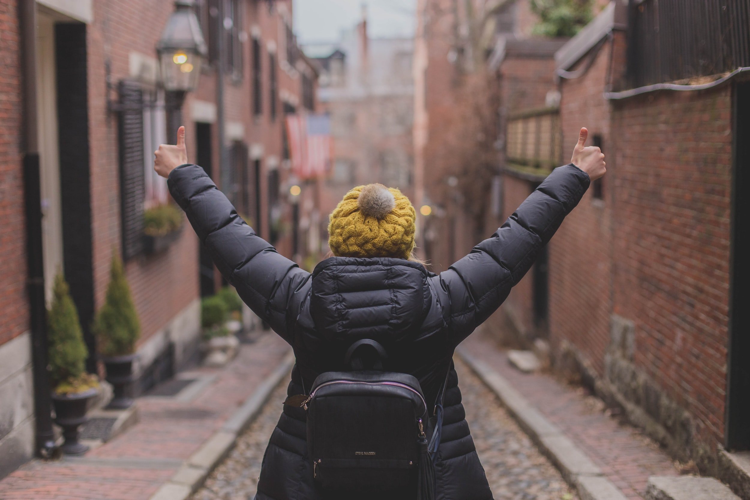 Lady walking down a street with her thumbs up.