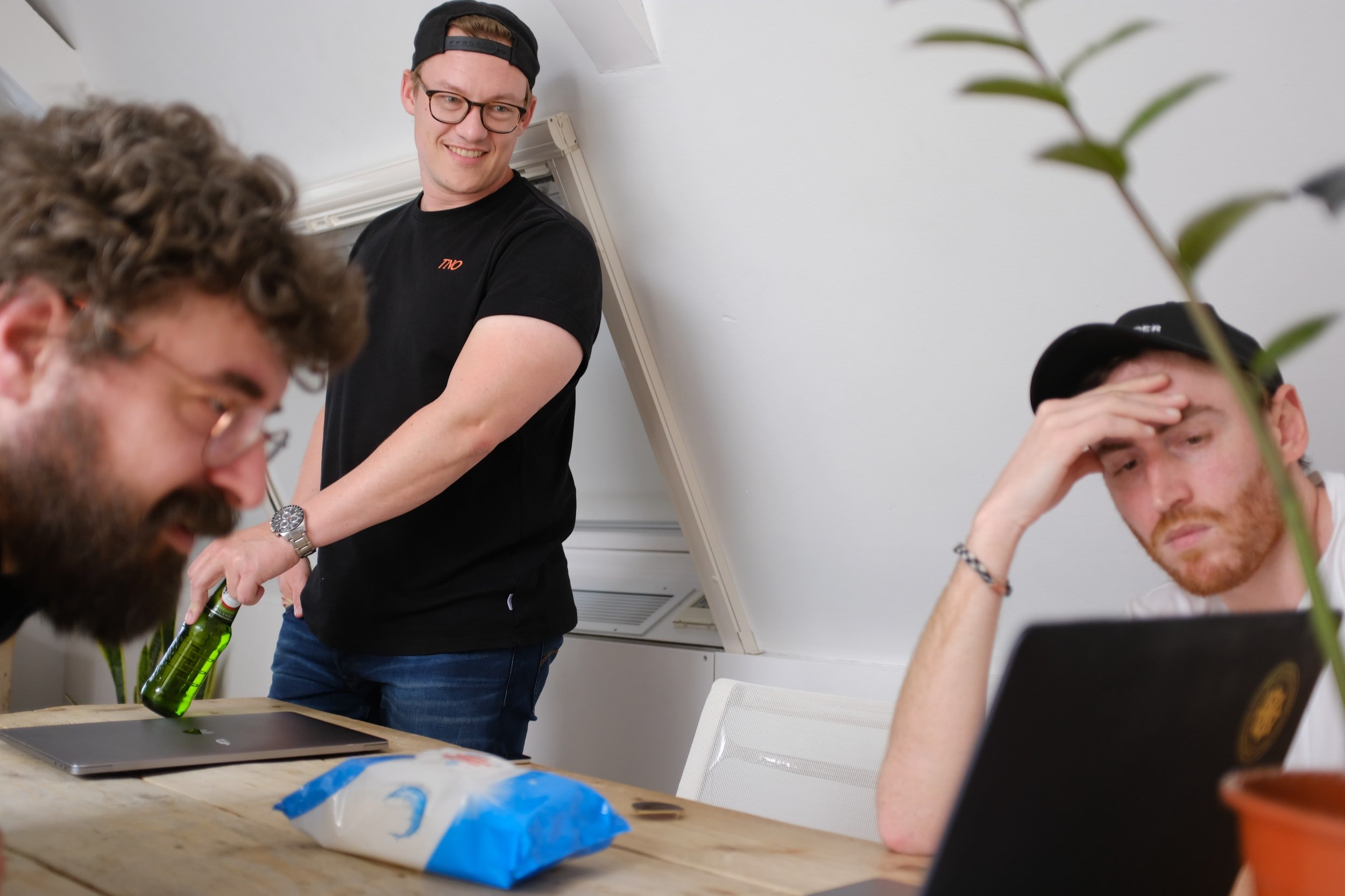 Three people converse while staring at a laptop screen.