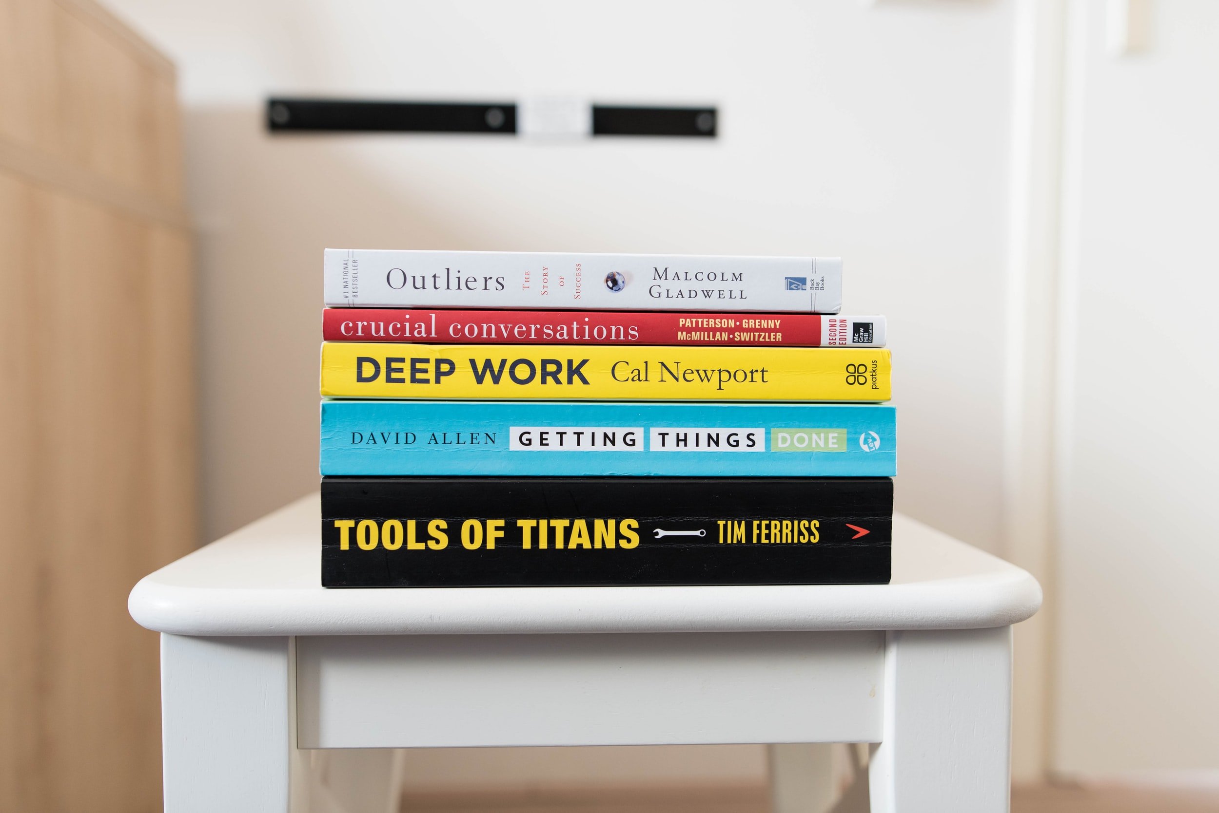 A stack of books on a small table, including the book Deep Work by Cal Newport.