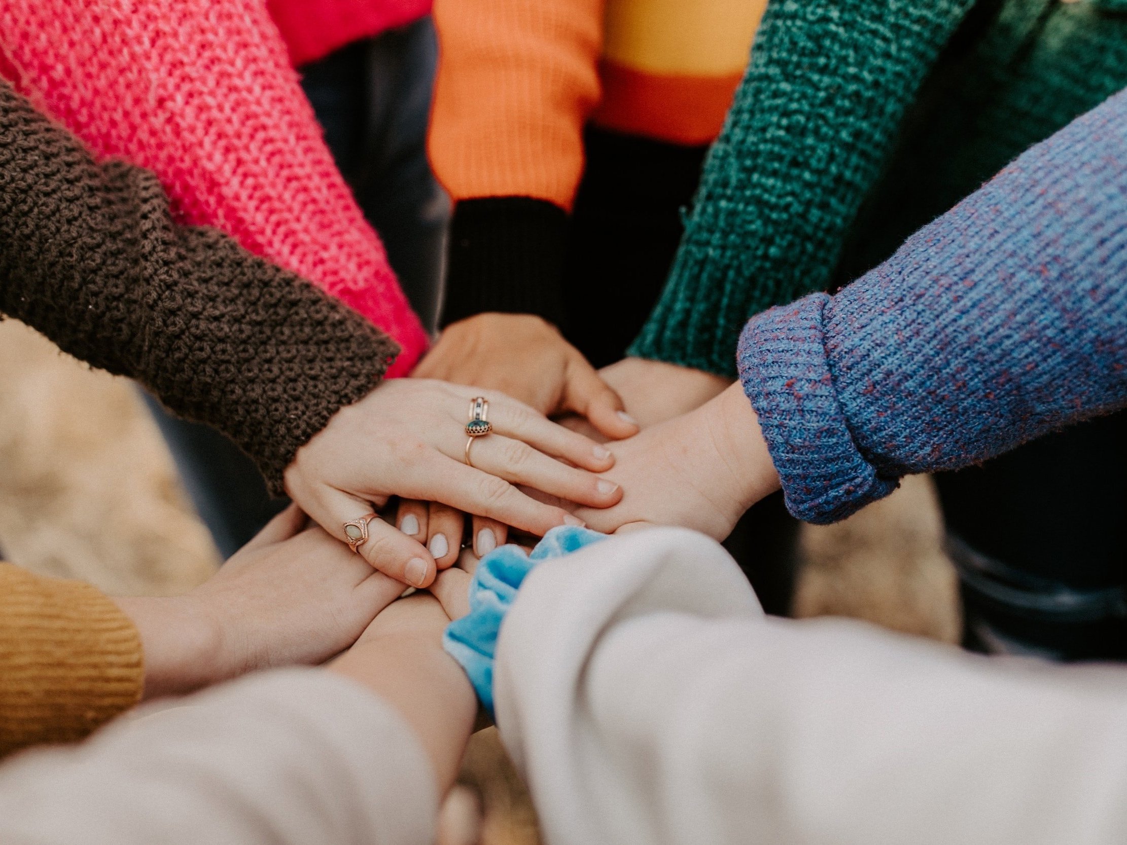 A group of women have their hands stacked on top of each other in a circle.