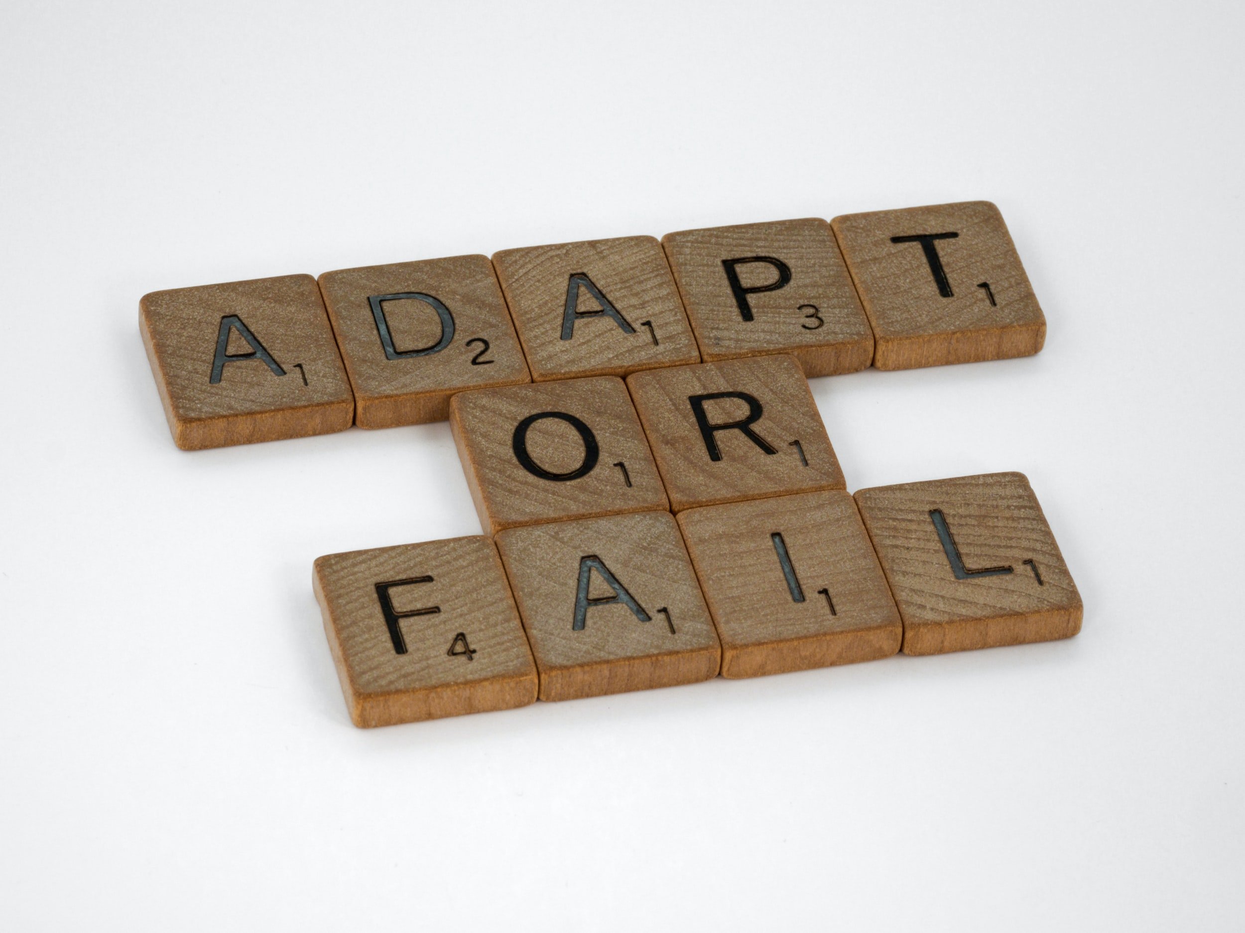 Adapt or Fail is spelled out with wooden letter tiles.