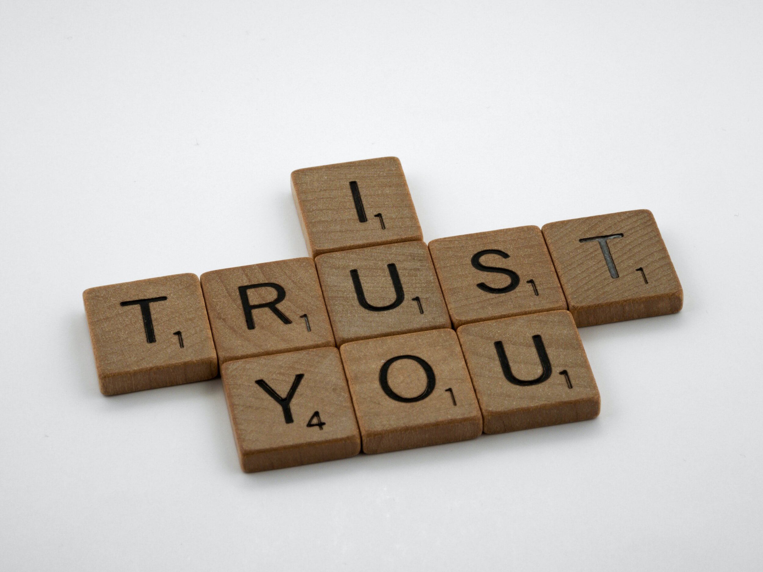 The phrase "I Trust You" is formed by wooden letter tiles.