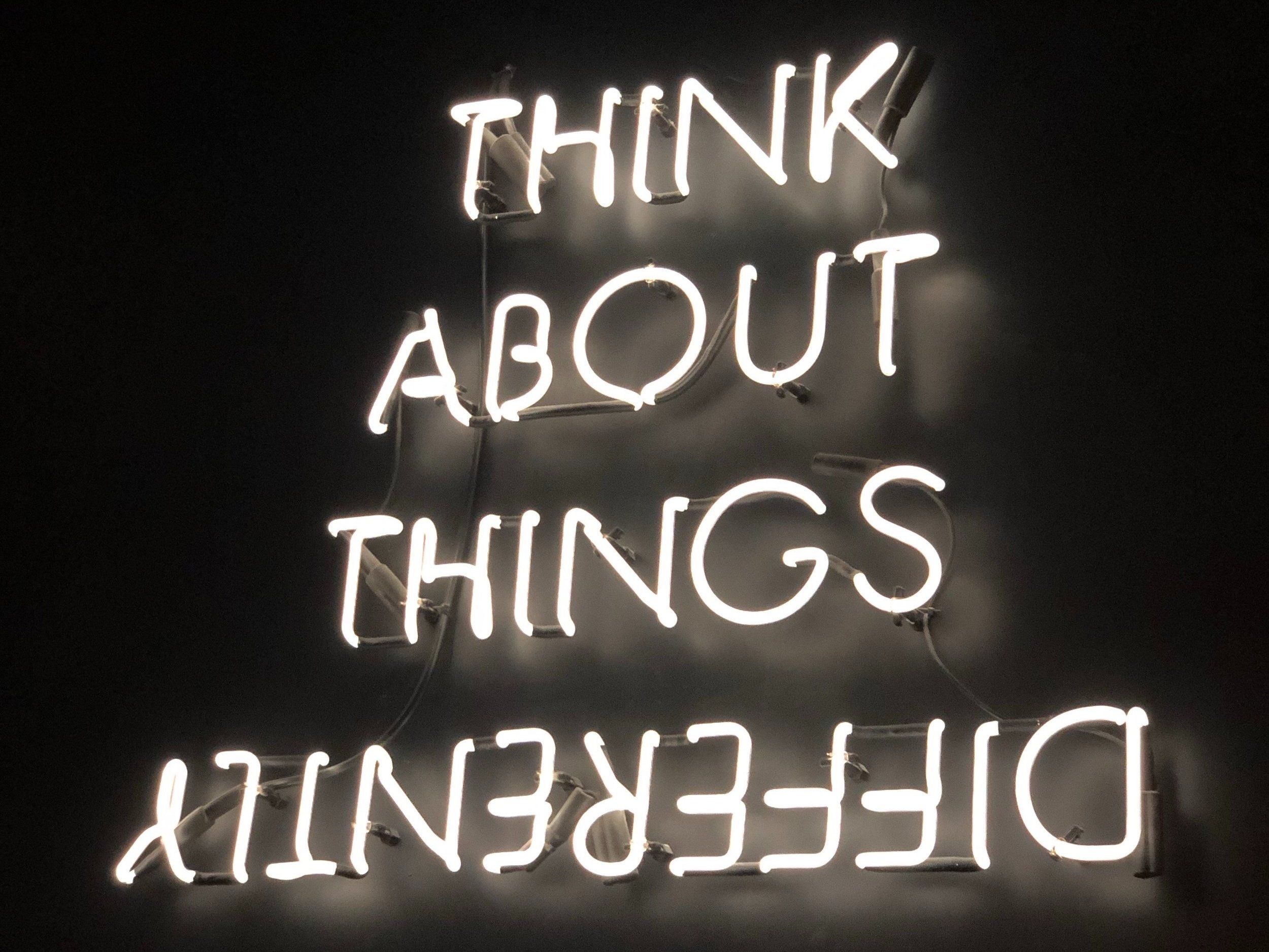 The words "Think About Things Differently" are illuminated in neon.