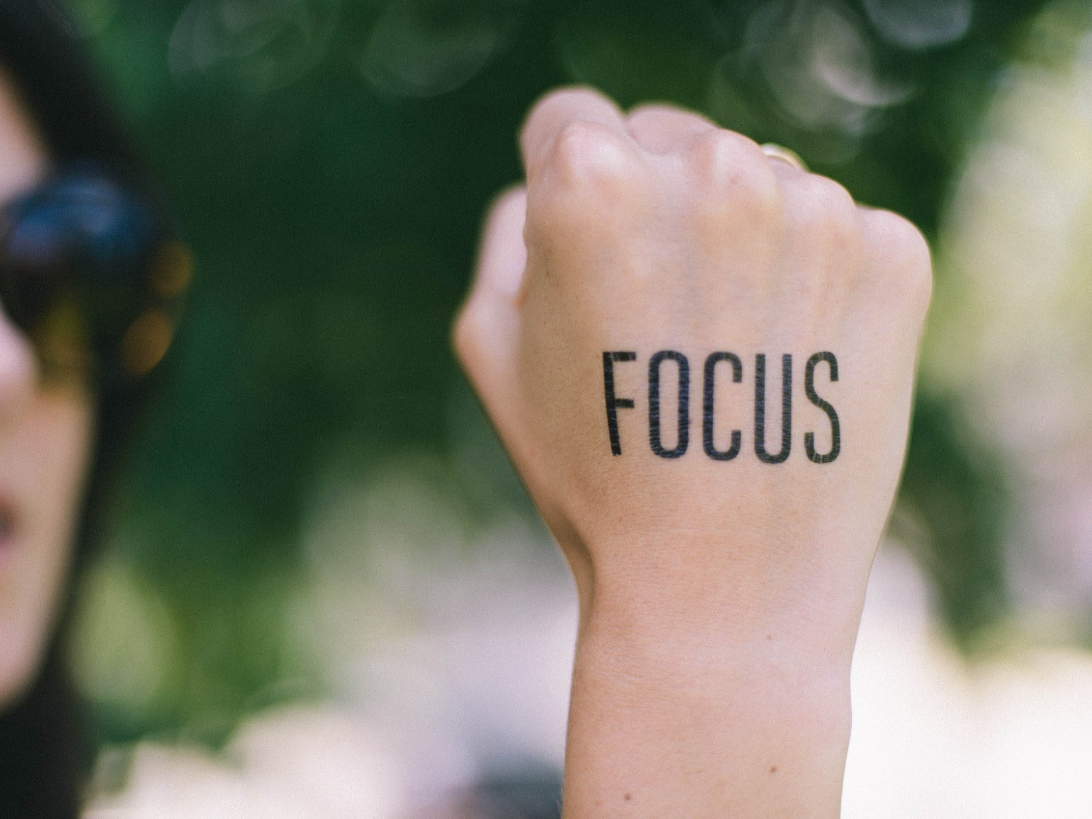 A lady clenches her fist, displaying a temporary tattoo spelling the word "Focus."