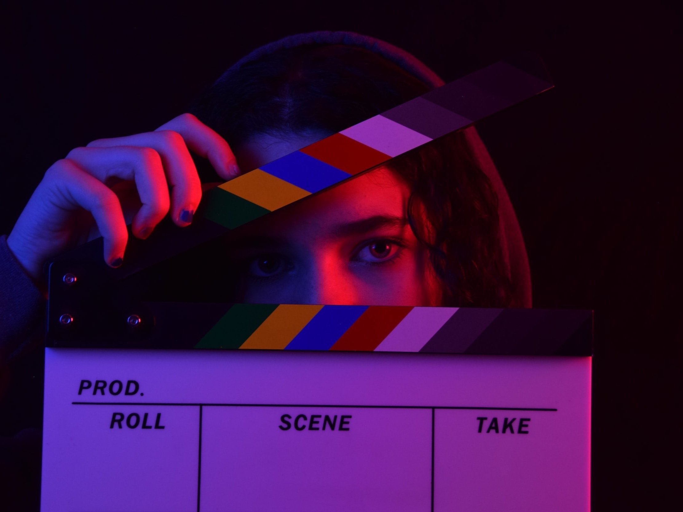 A woman peering through a cinema clapperboard