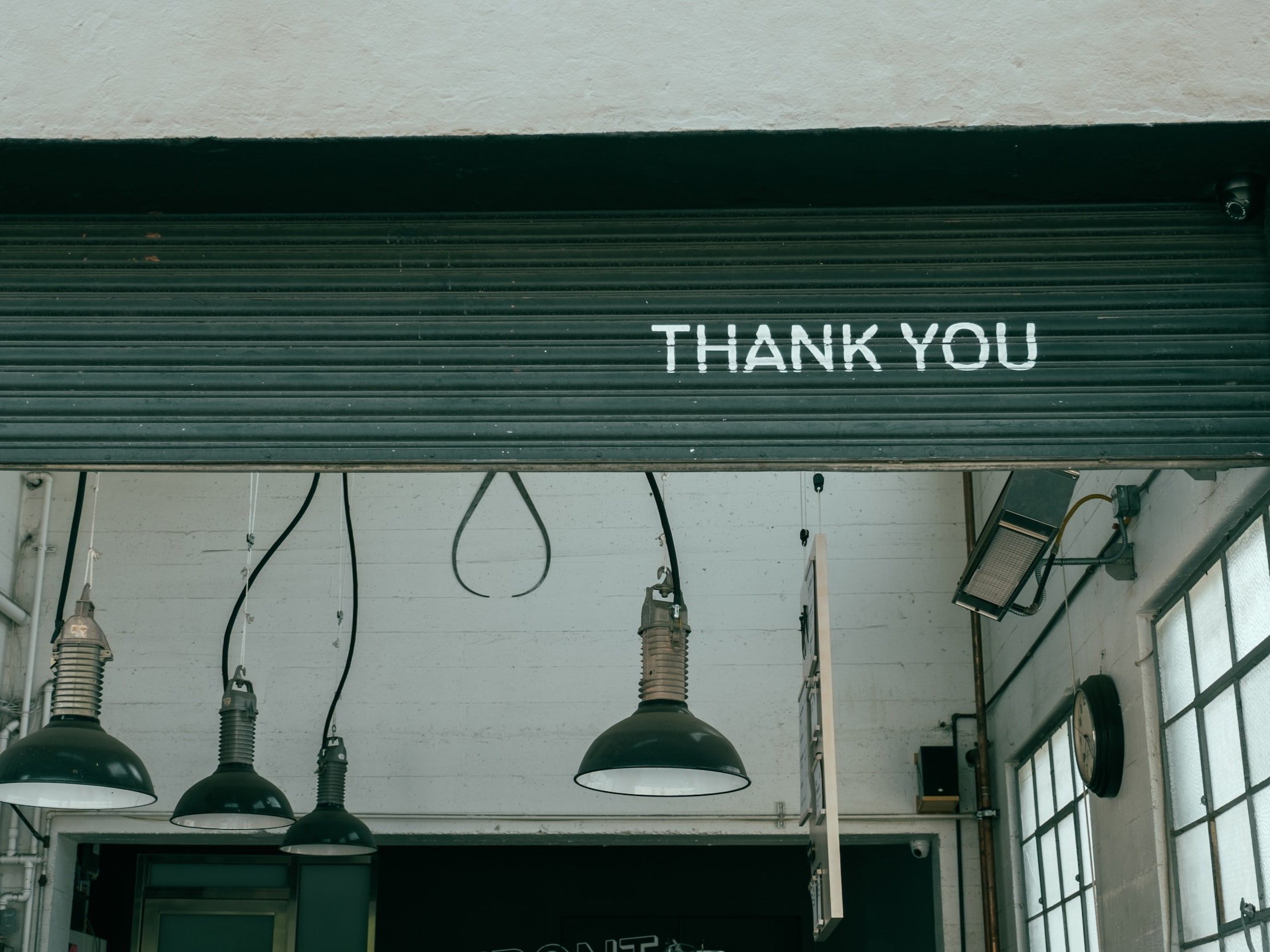 A workshop with rolled-up roller shutters with the words "Thank you" painted on them.