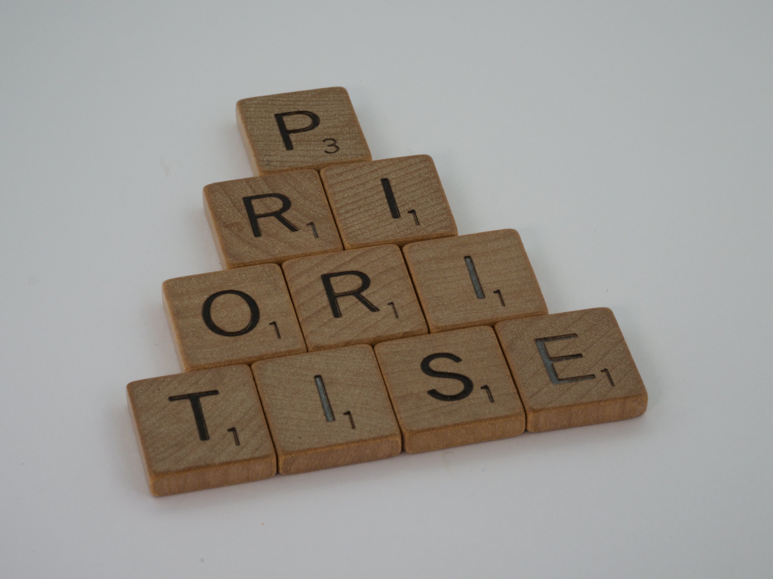 The word "prioritise" is written in wooden letter tiles.