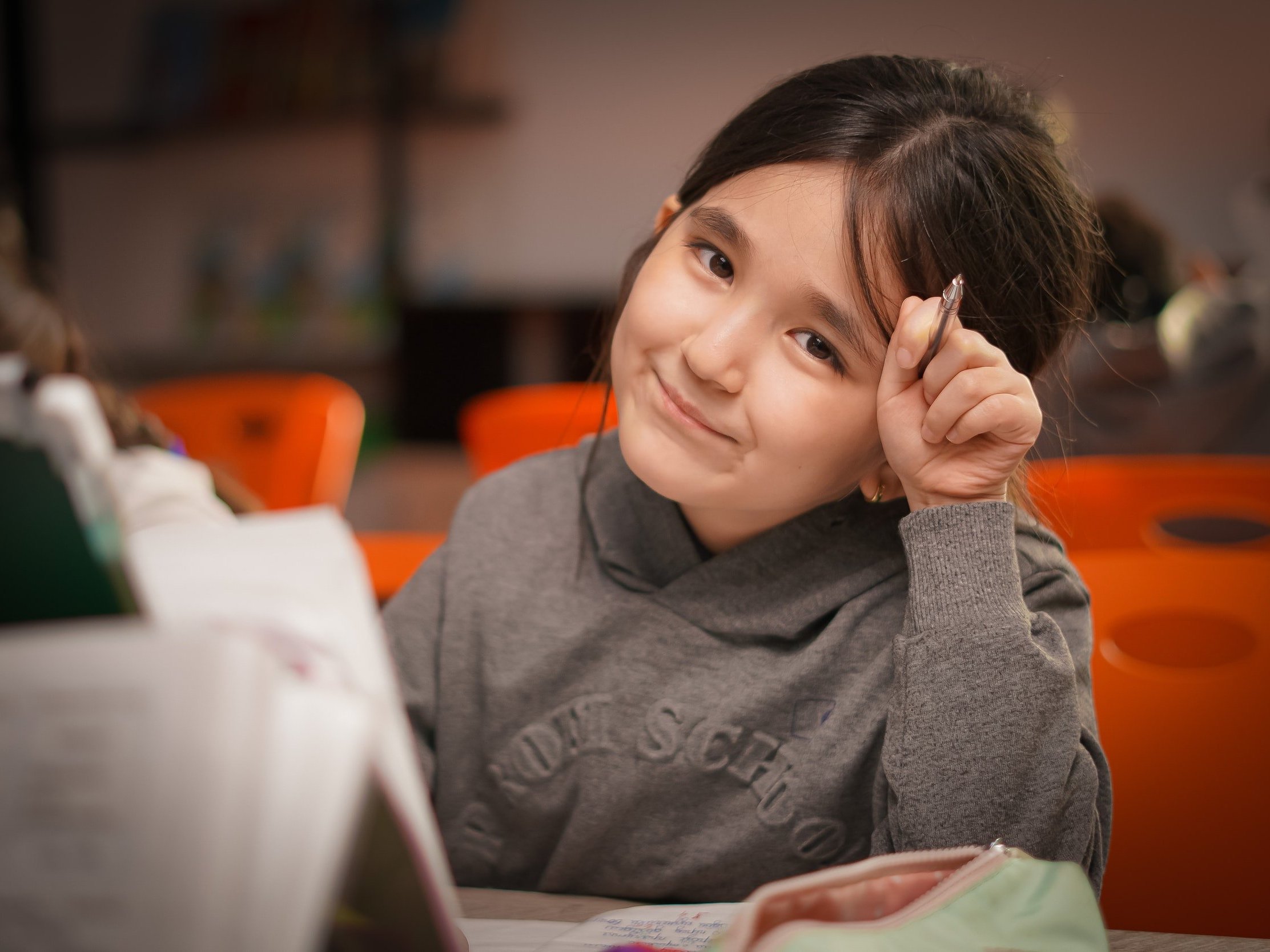 While studying at a school desk, a youngster smiles.