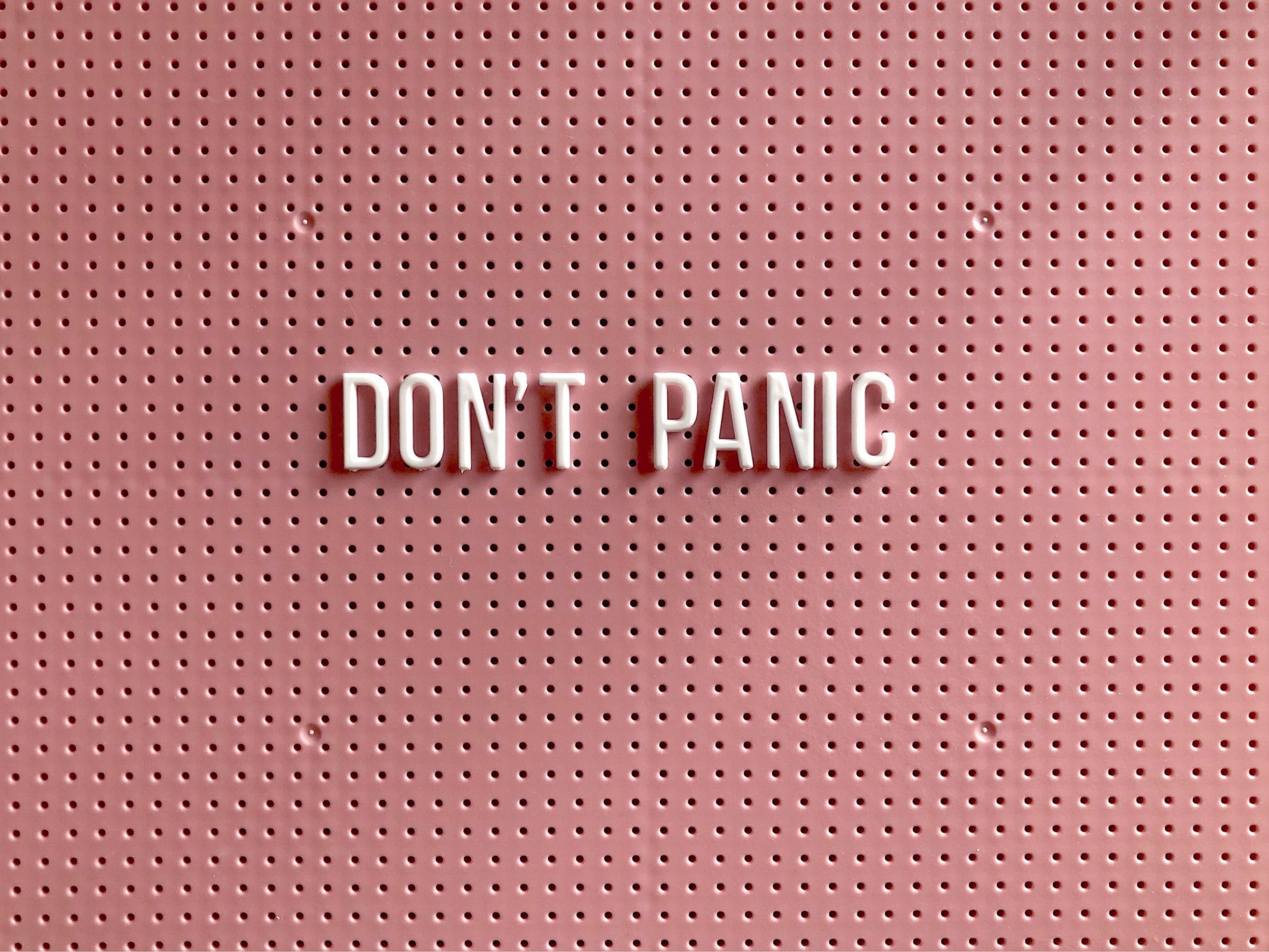 Plastic letters on a pegboard spell out "Don't Panic."