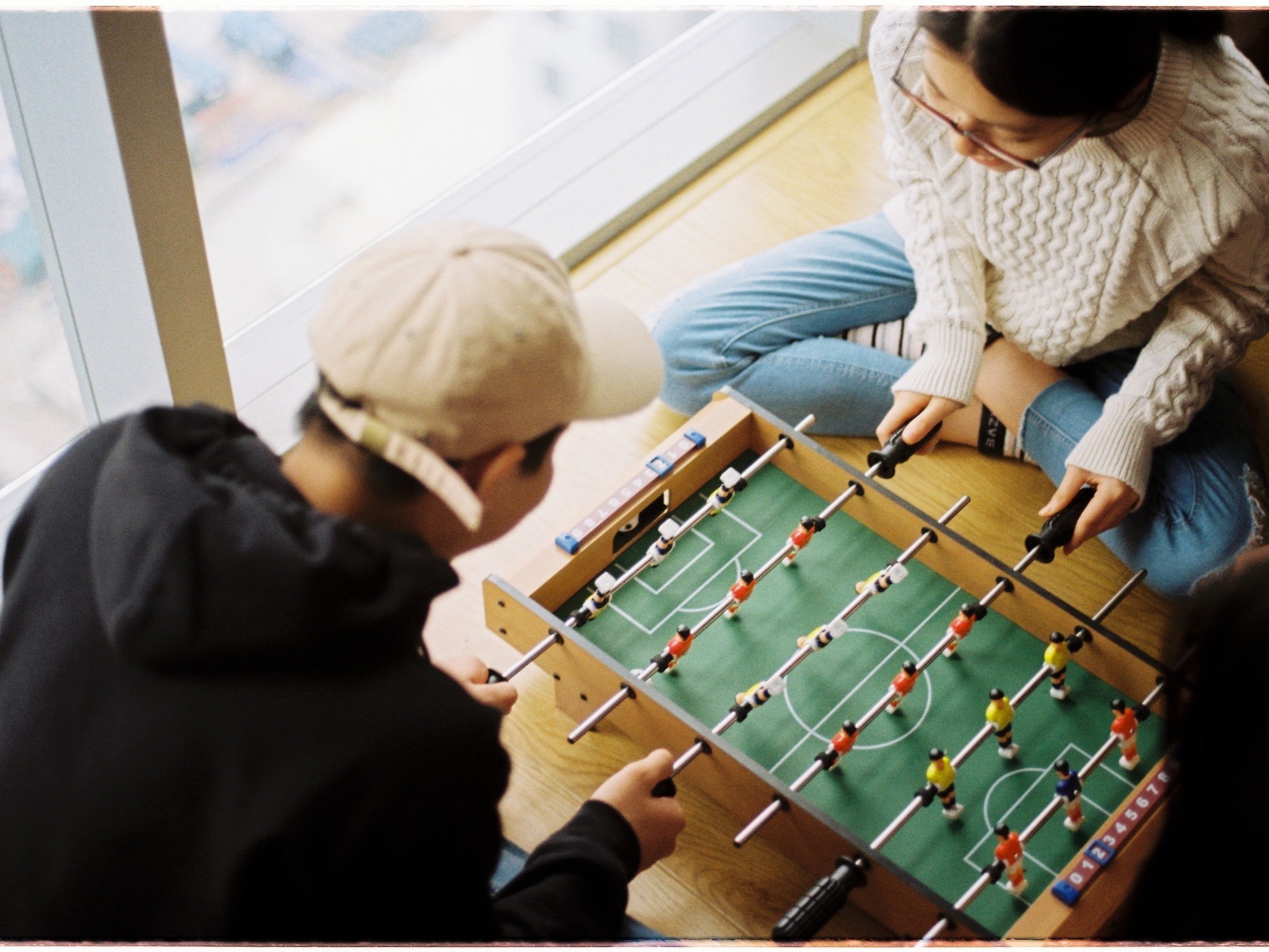Two people are enjoying themselves by playing mini-table football.