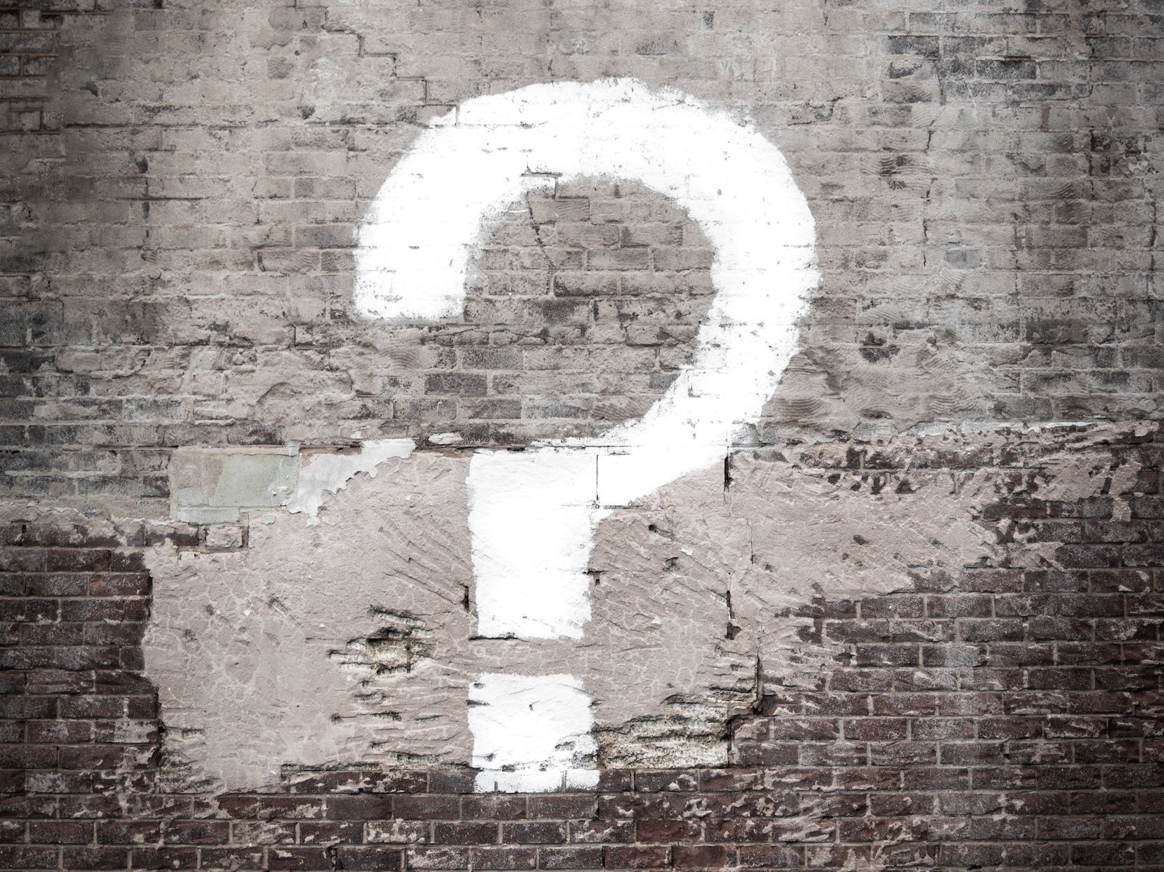 A white question mark is painted on a wall outside.
