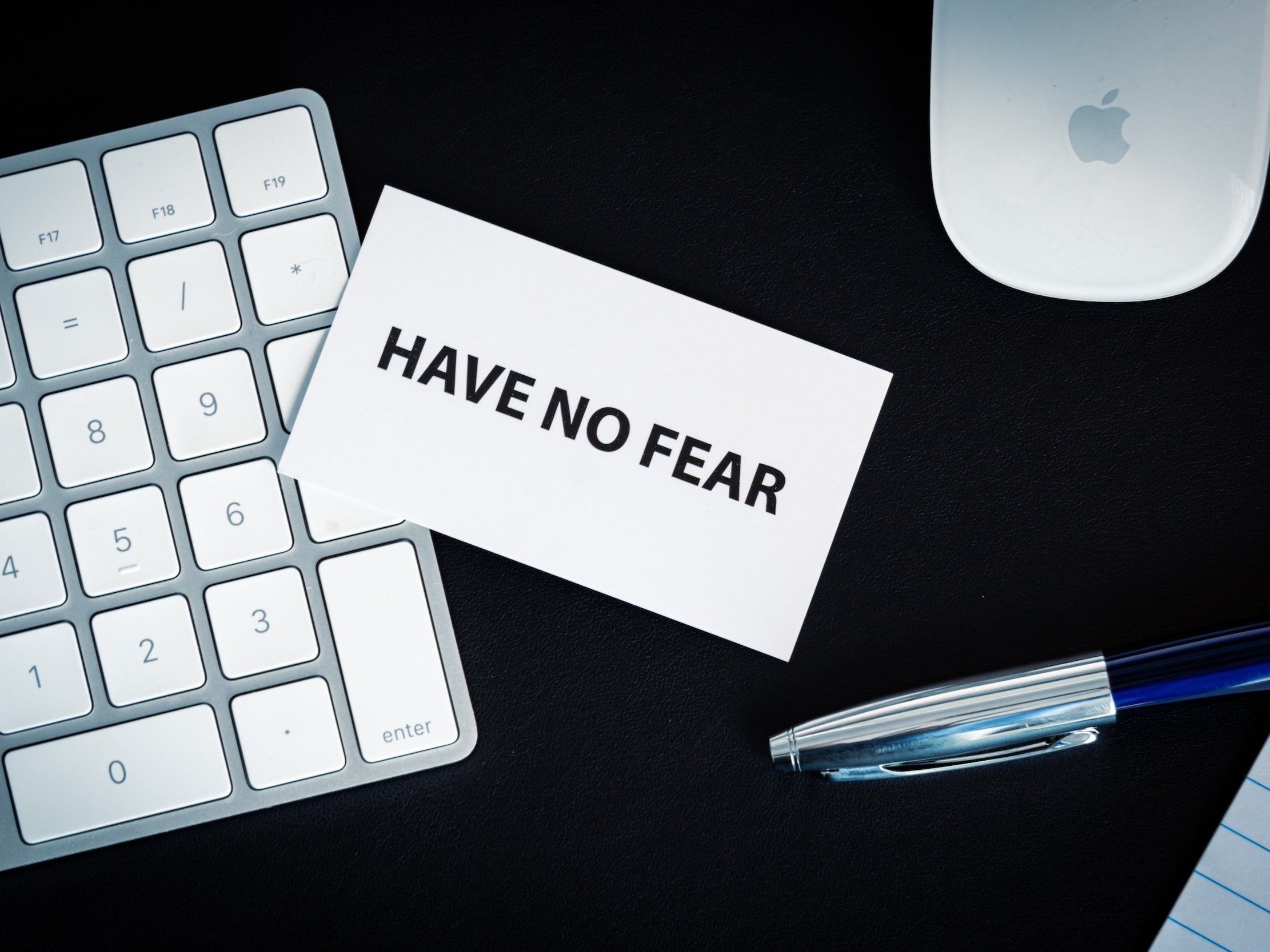 A business card with the words "Have No Fear" resting on the numeric keys of an Apple keyboard.