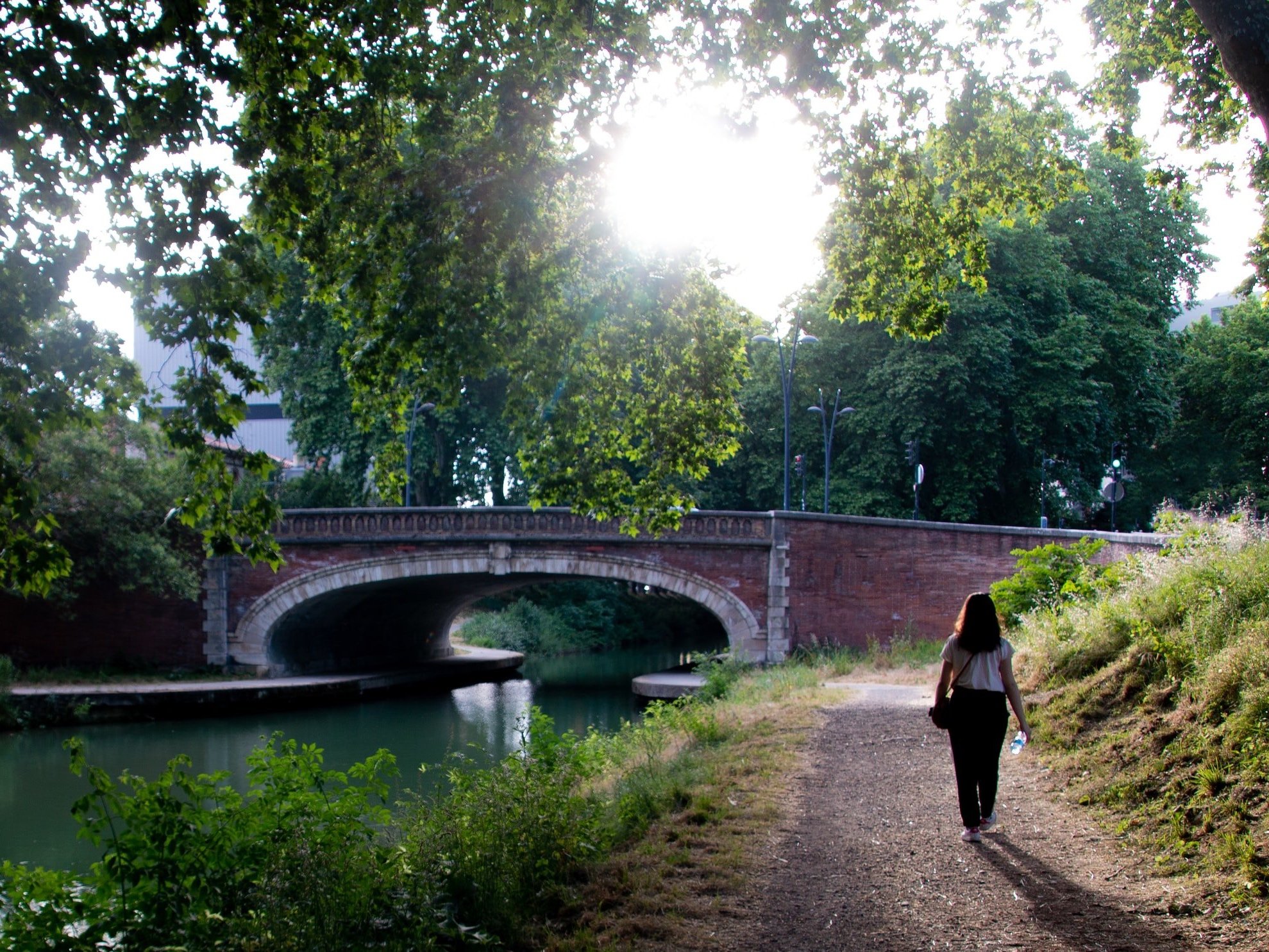 Early in the morning, a person walks along the canal.
