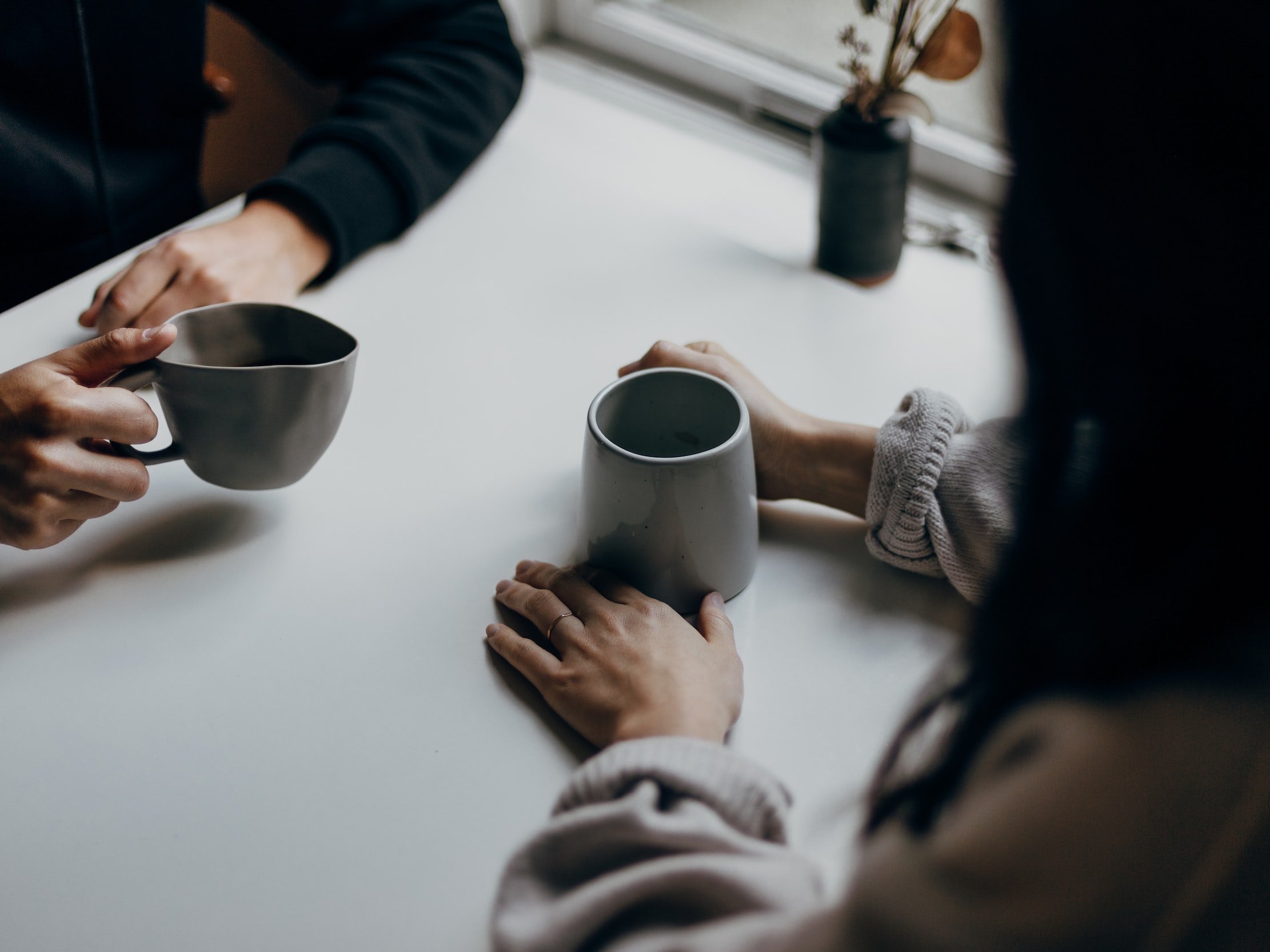 Two people conversing over a cup of coffee at a table