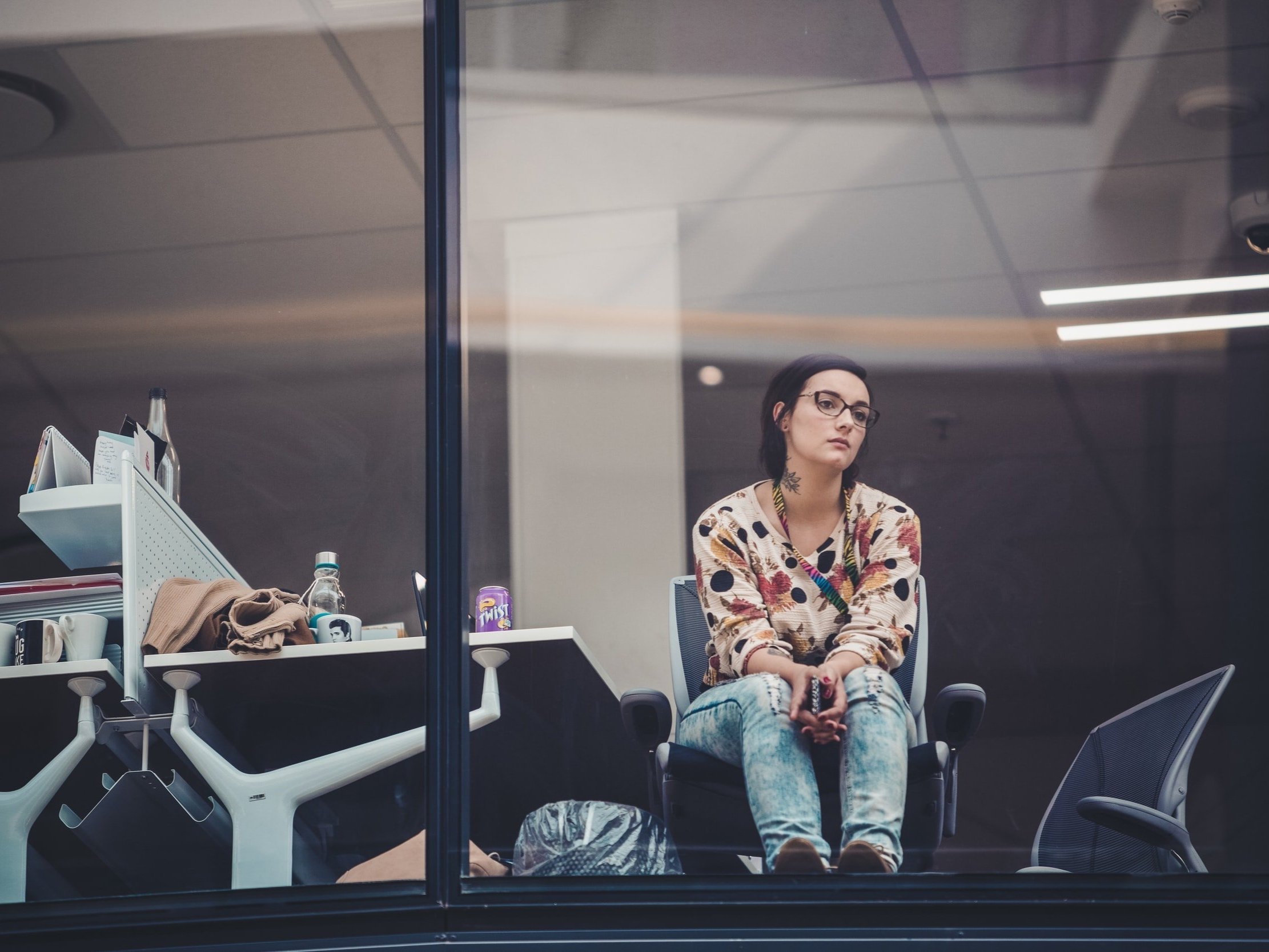 A young woman at work, staring out the window, appears to be bored.