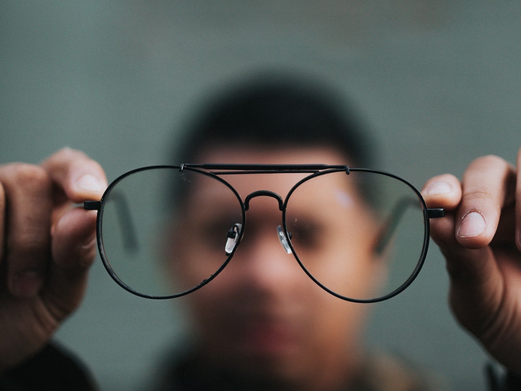 A man holds out a pair of glasses, emphasising vision and clarity.