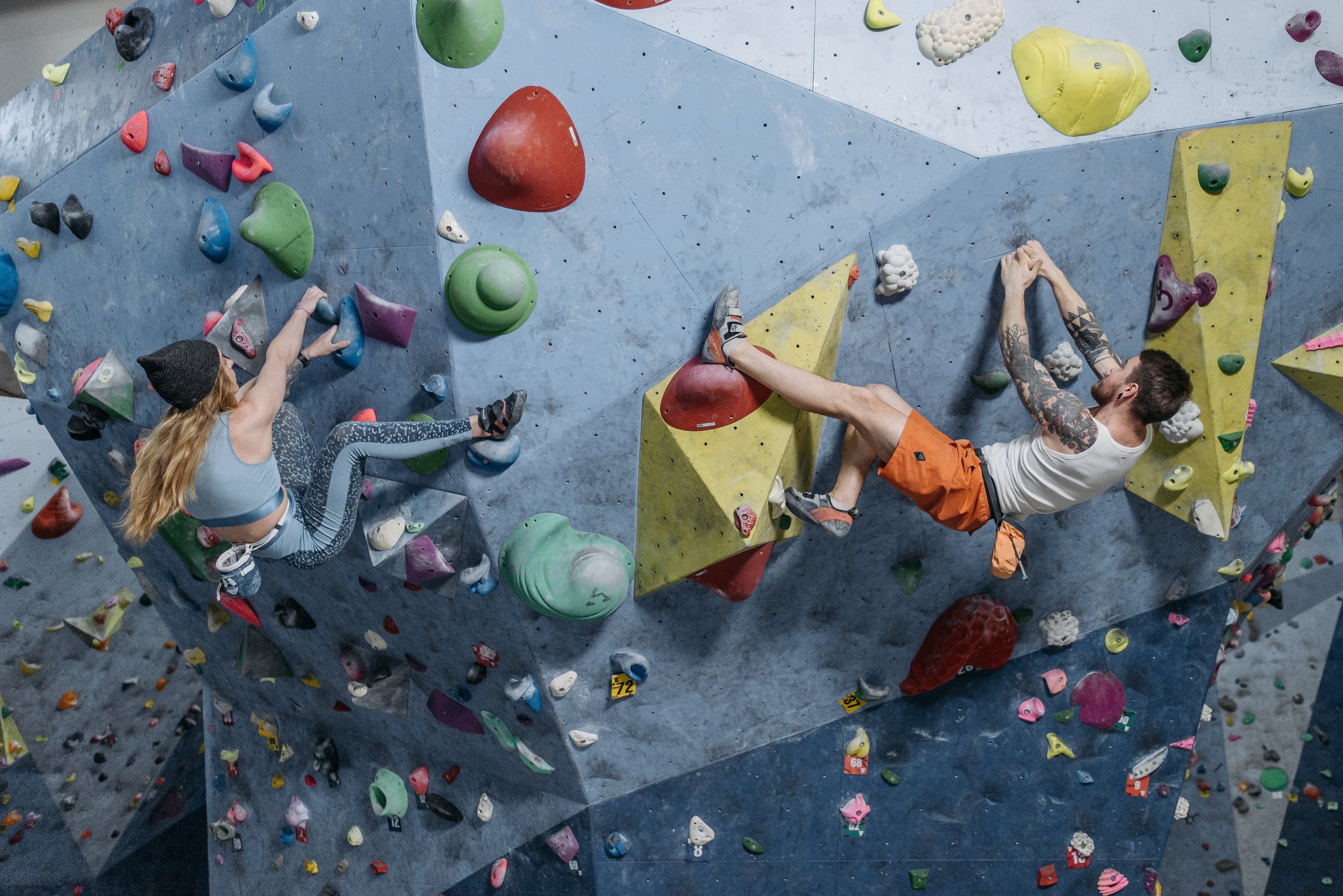 a man and a woman scaling a climbing wall