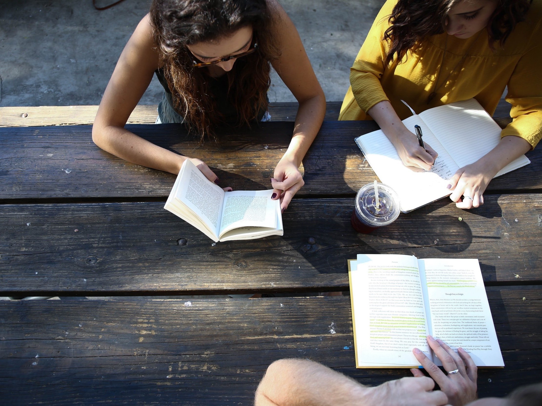 People reading and writing while sitting on a bench