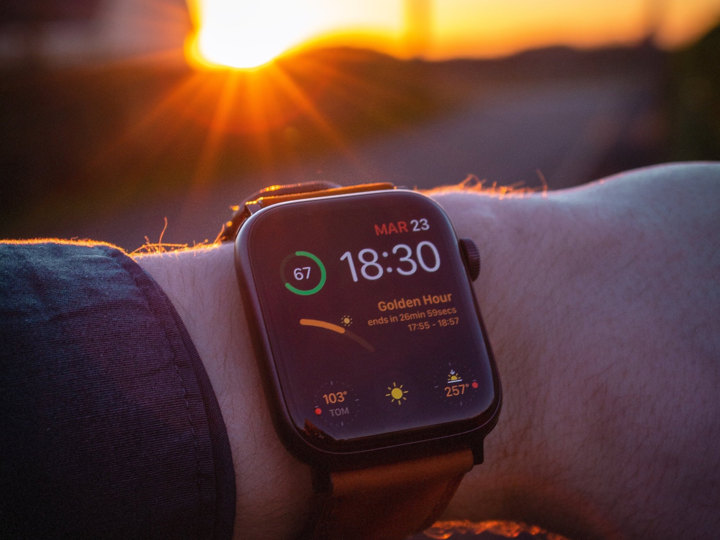 A person looking at his Apple Watch in front of the summer sun.