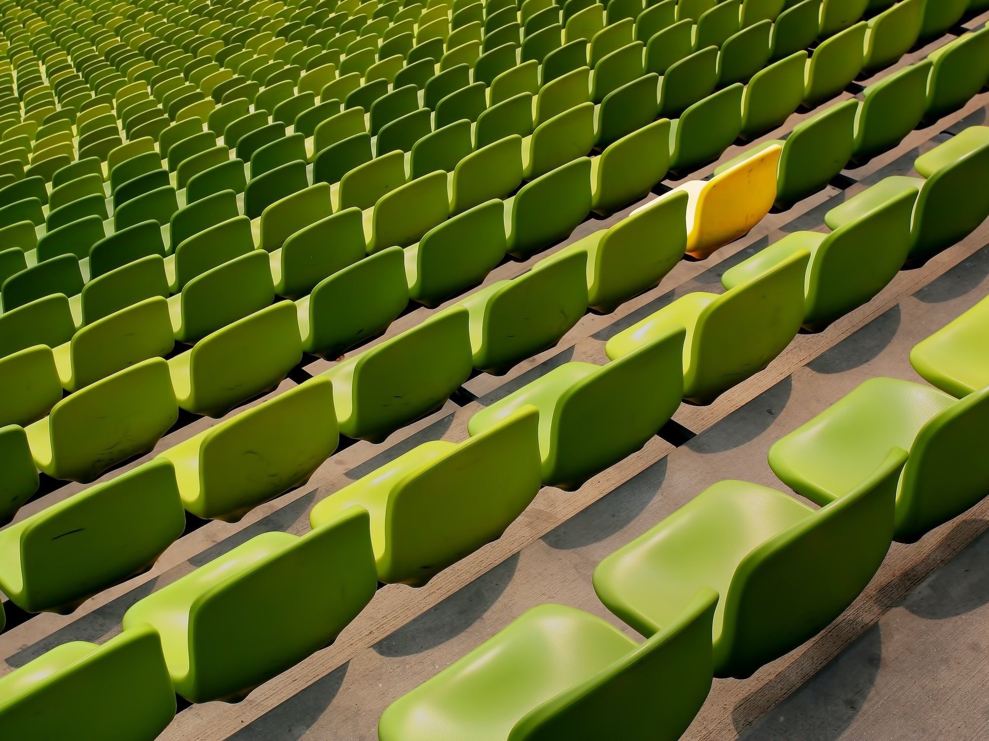 A yellow chair stands out among the other green chairs.