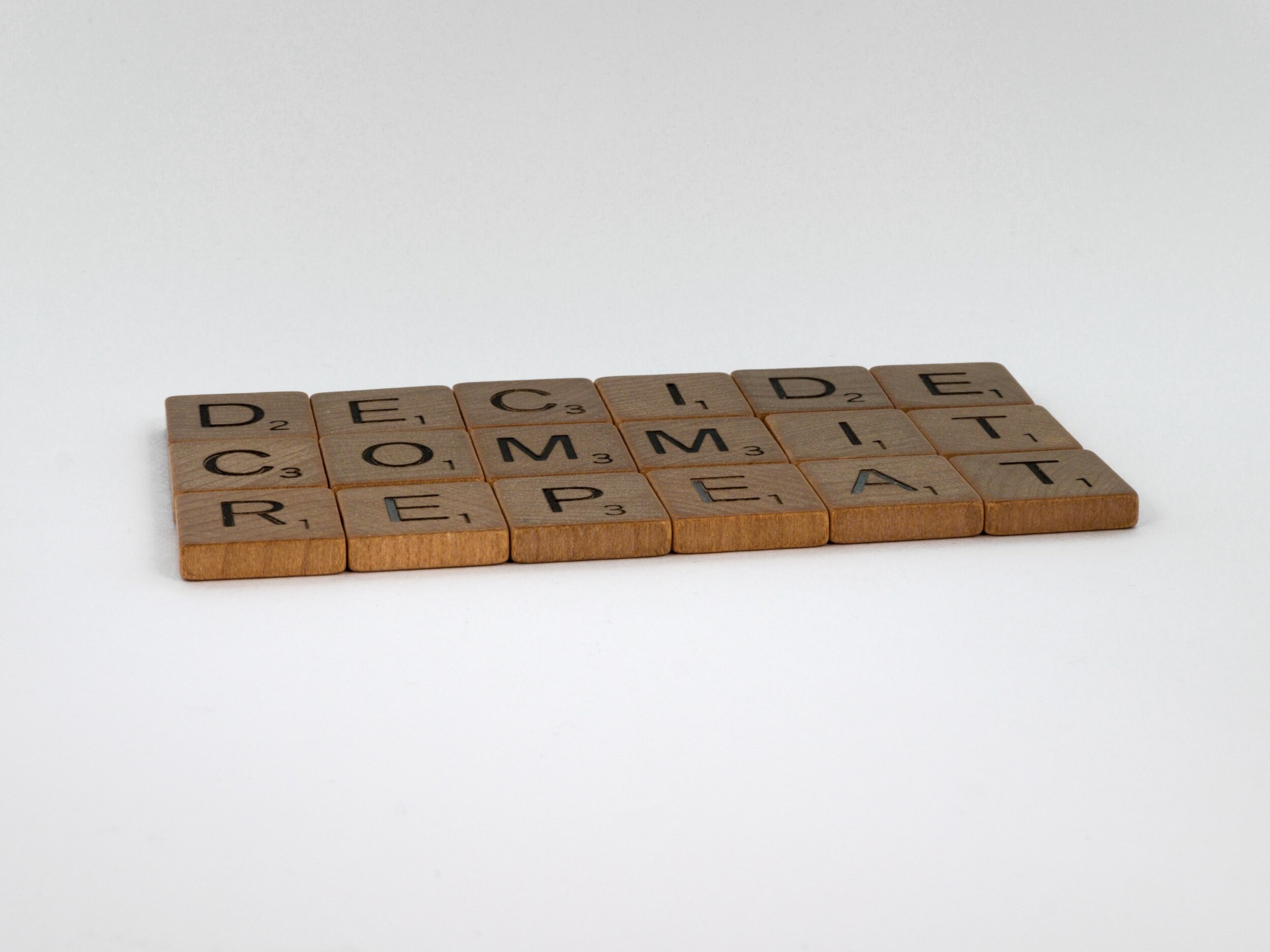 In wooden letter tiles, the words "Decide, Commit, and Repeat" are written.