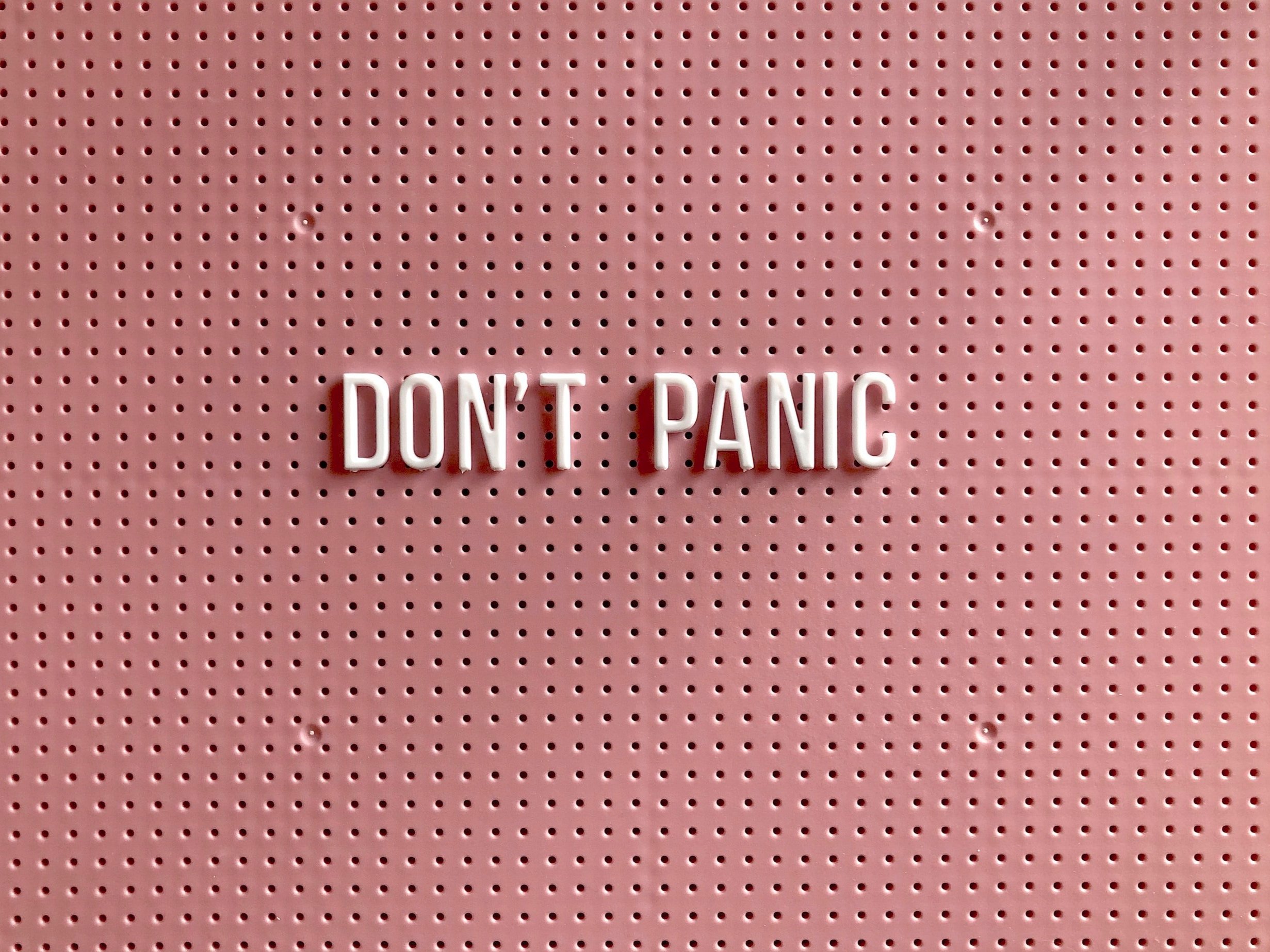 On a peg board, the words "Don't Panic" are spelled out.