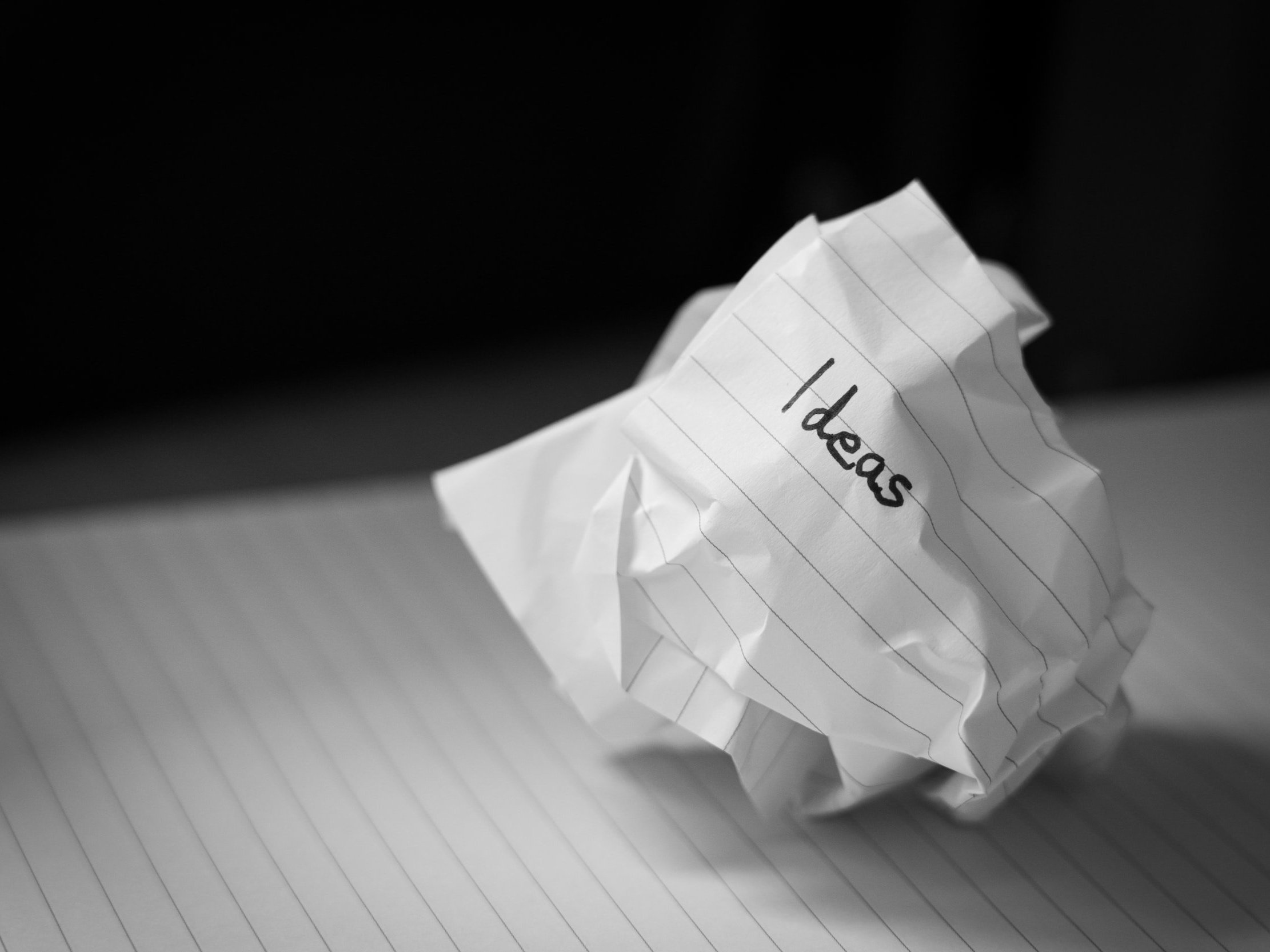 A crumpled sheet of paper with the word "ideas" scrawled on it.
