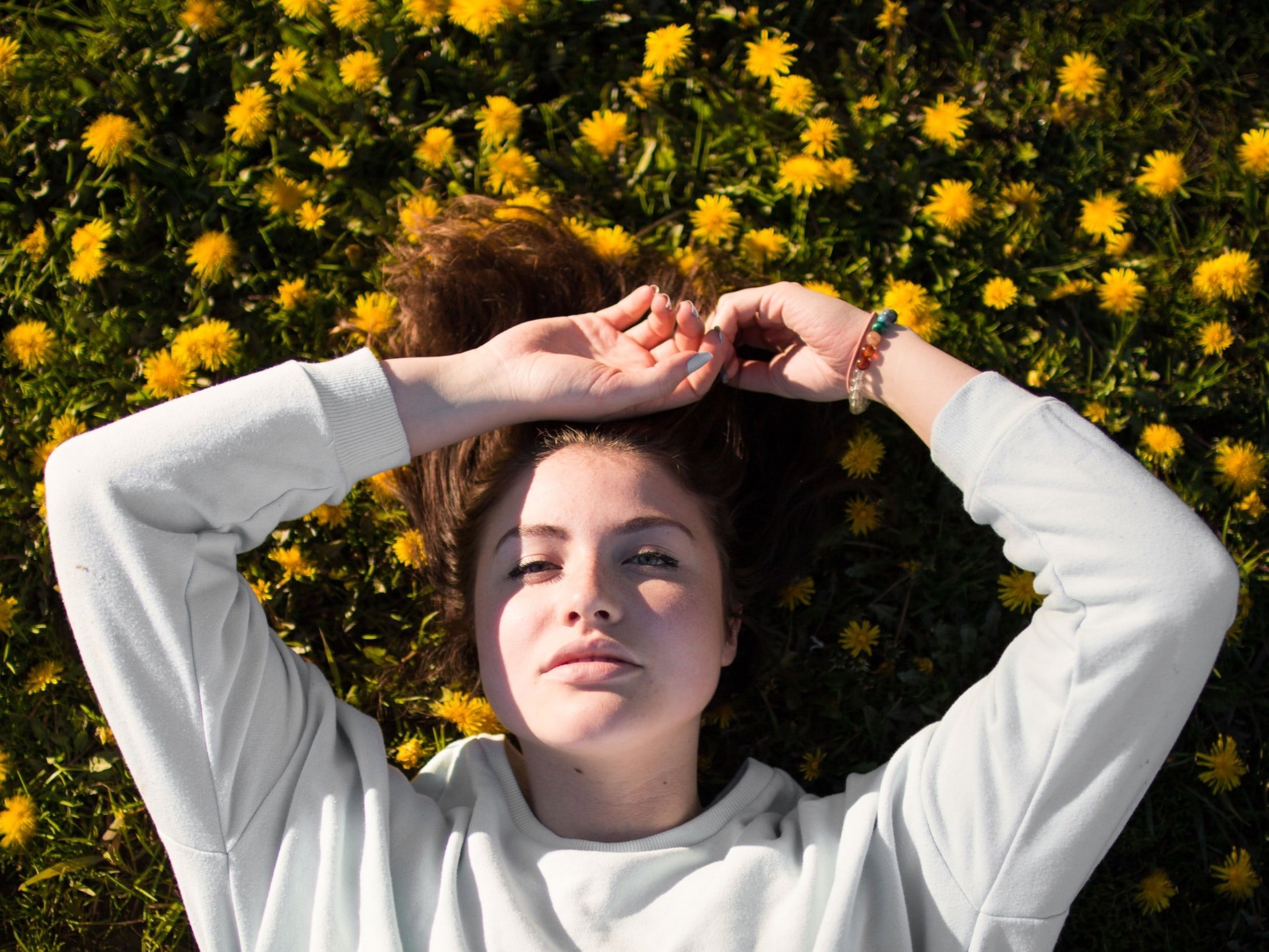 A girl relaxing while lying among the dandelions