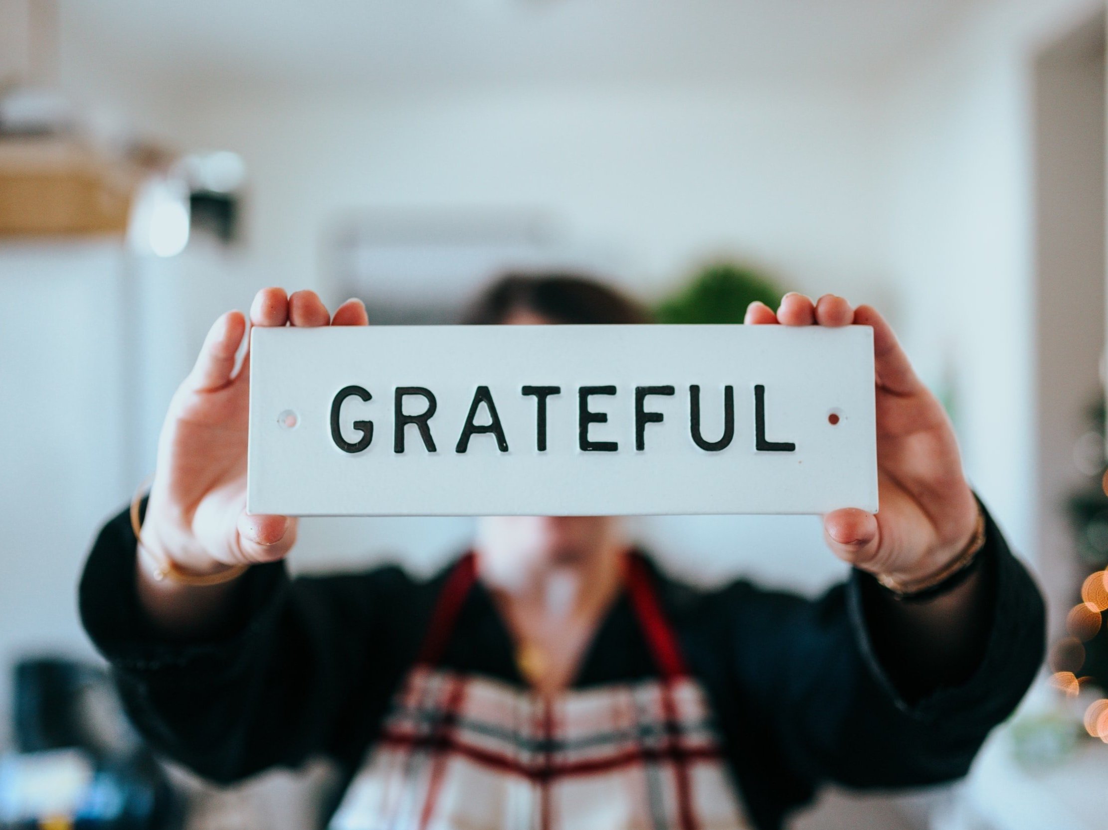 A person holding a plaque inscribed with the word grateful.