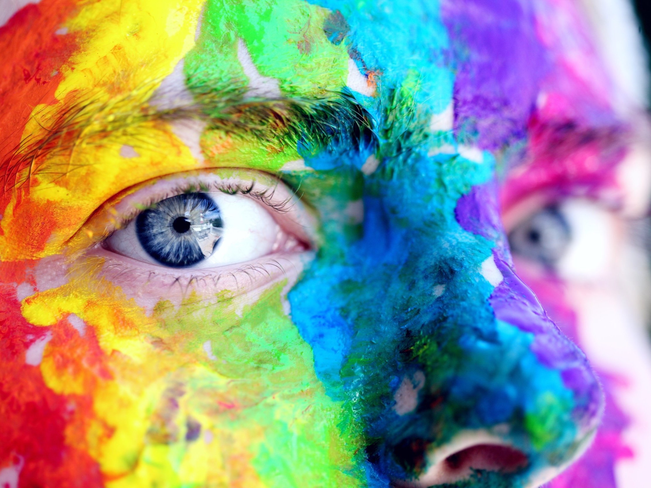 A person wearing multicoloured body paint is staring at you.