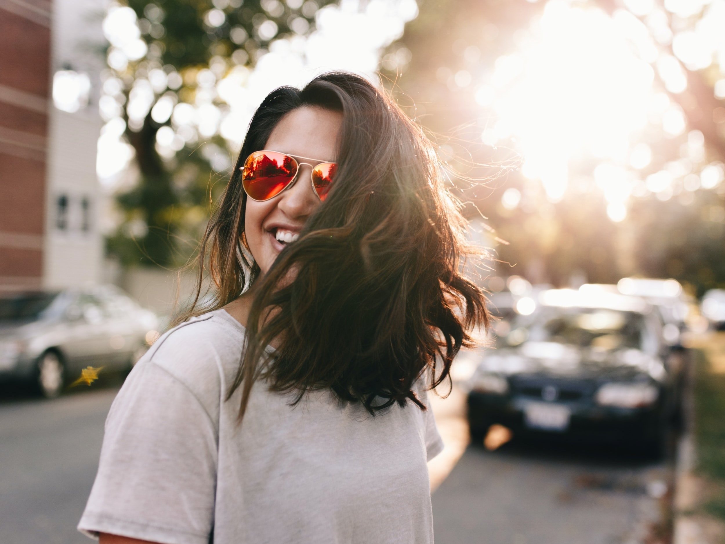 A woman wearing sunglasses is beaming and overjoyed.