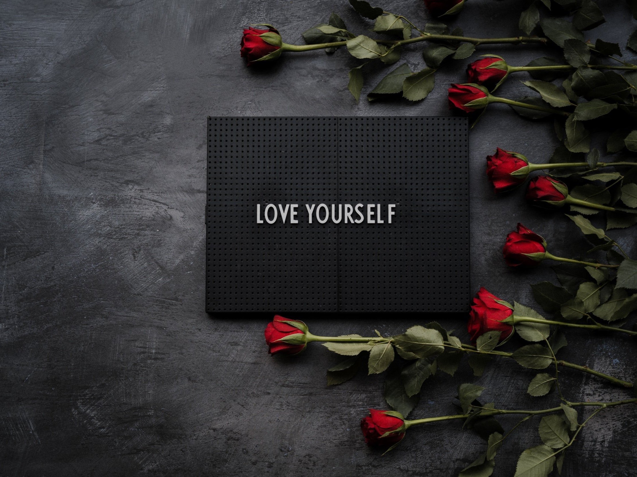 a peg board with the words "love yourself" written on it and surrounded by red roses